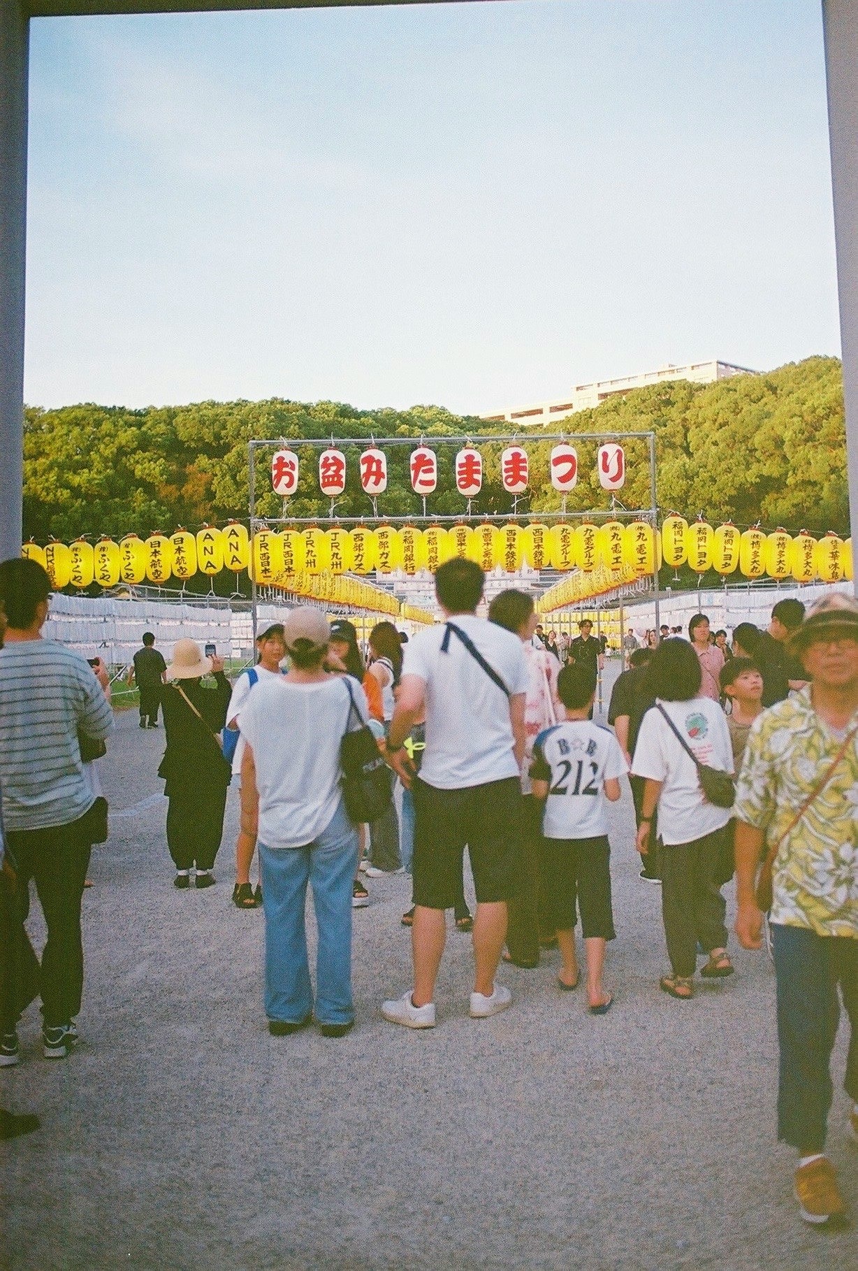 屋外のイベント会場で人々が並ぶ入場ゲート前の風景