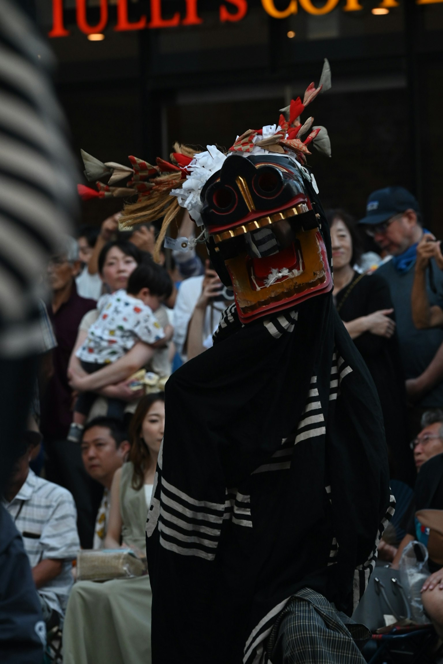 一位佩戴着色彩丰富传统面具的表演者在观众面前表演