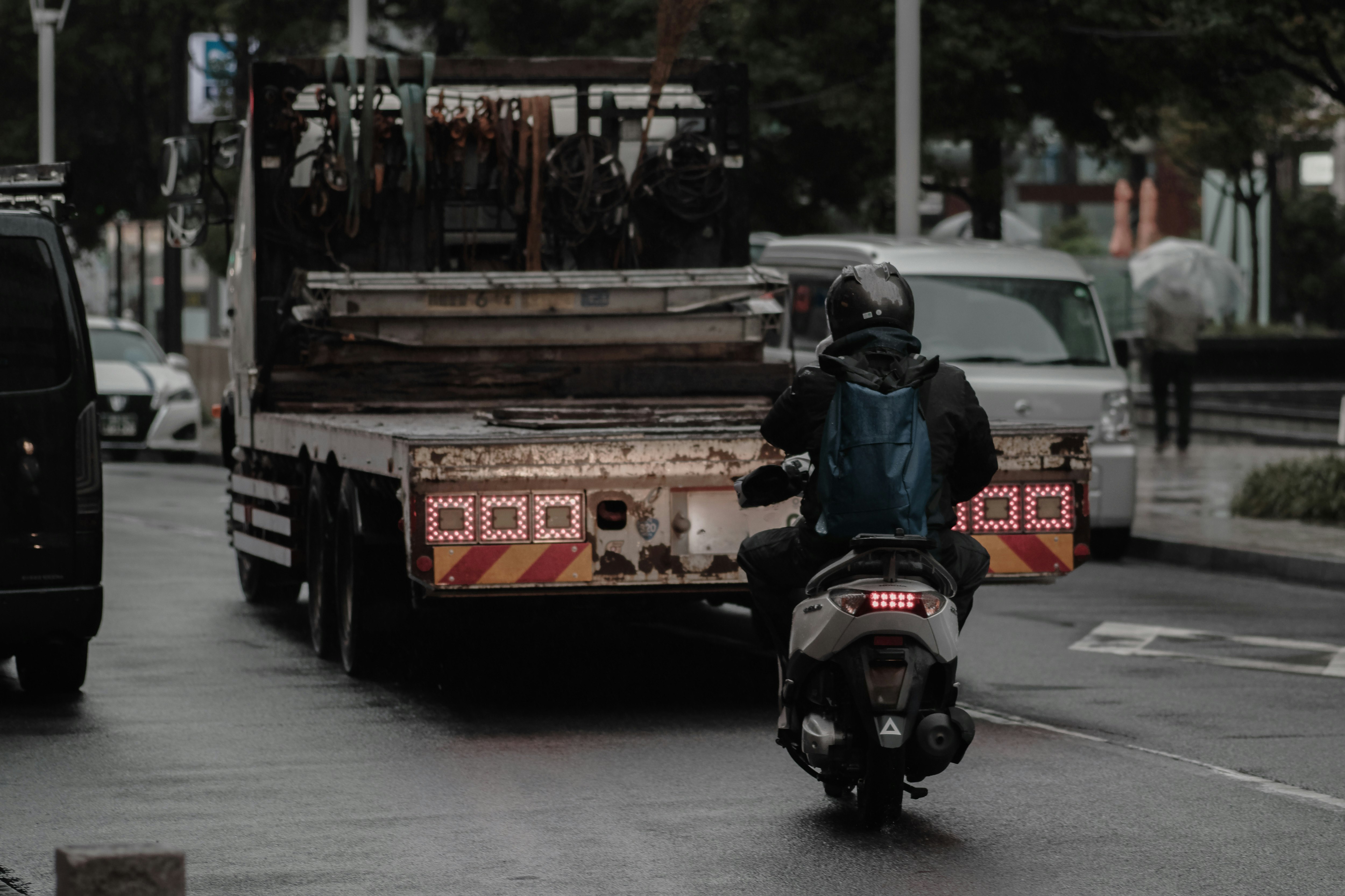 雨の街を進むトラックとバイクのある道路風景