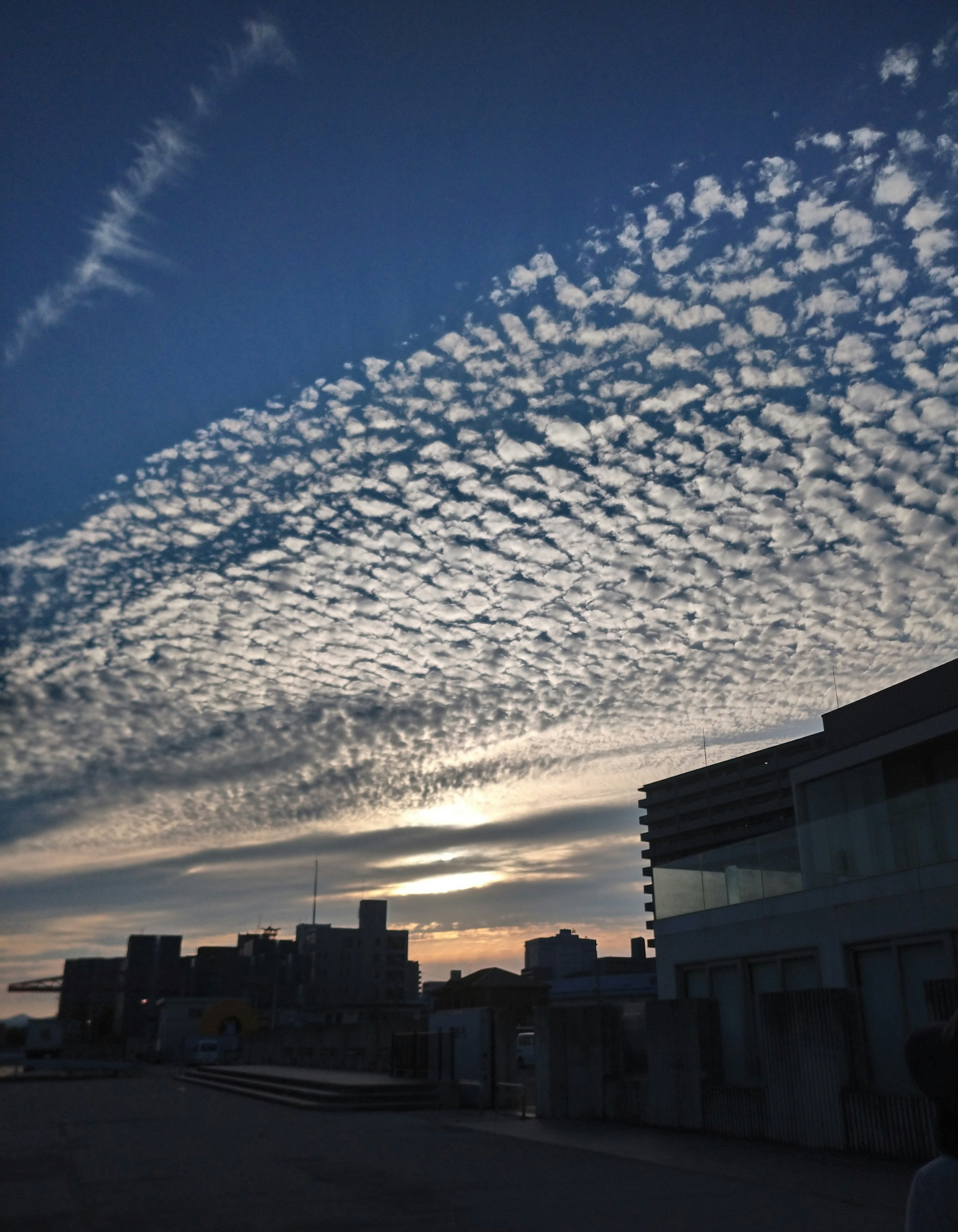 空に広がる雲の渦巻きと夕暮れの街並み