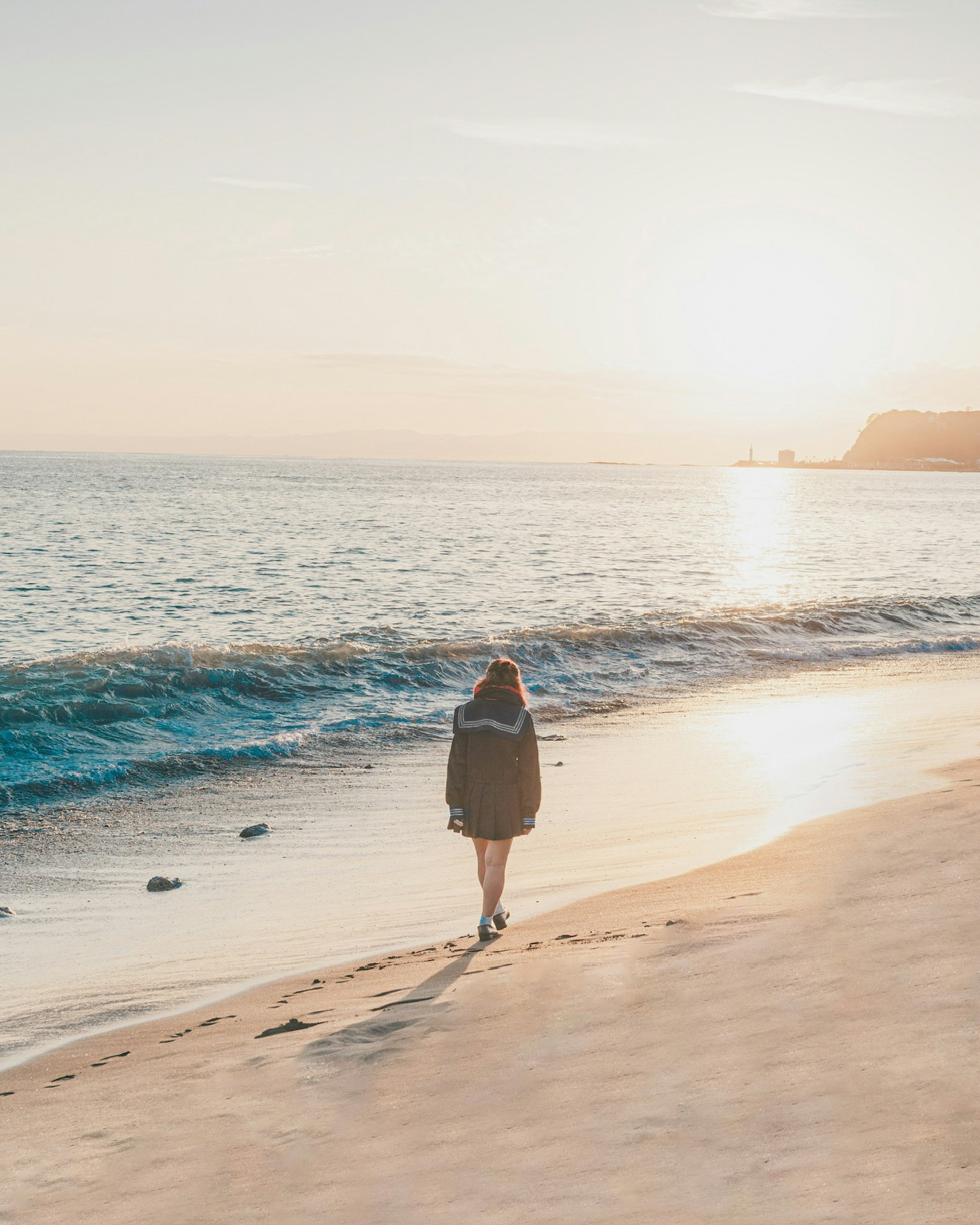 Silhouette of a woman walking along the beach at sunset