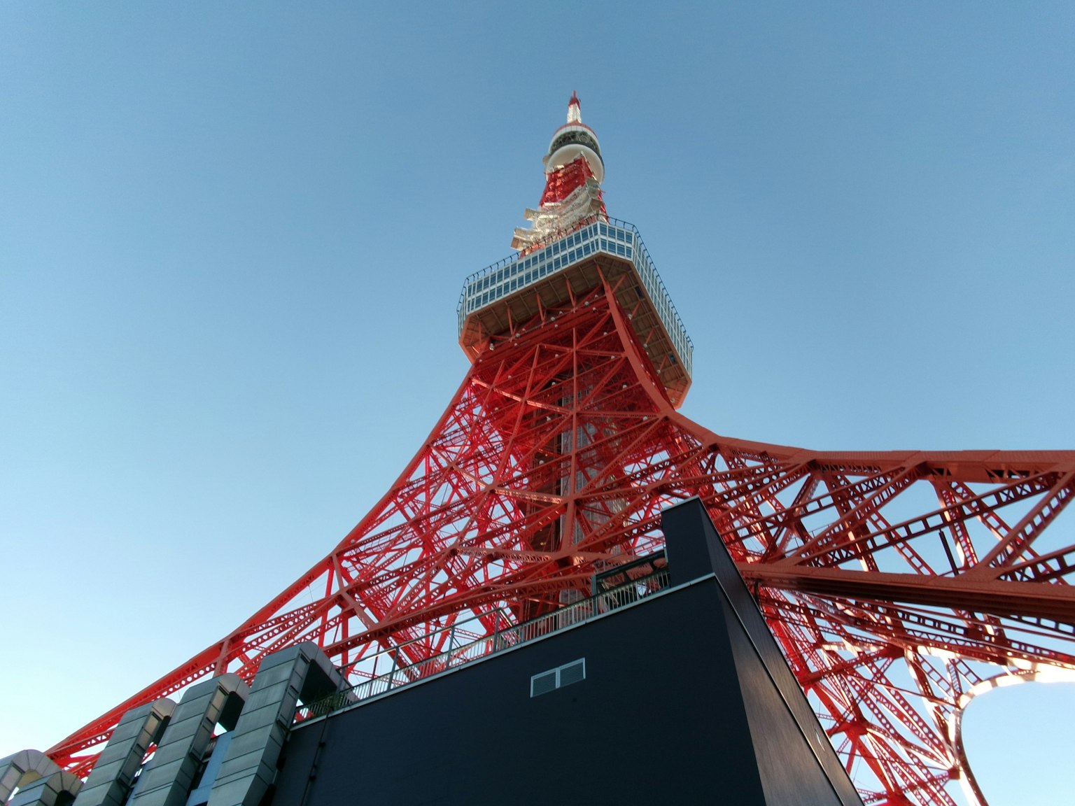 Vista de la Torre de Tokio desde abajo mostrando su estructura de acero rojo contra un cielo azul claro