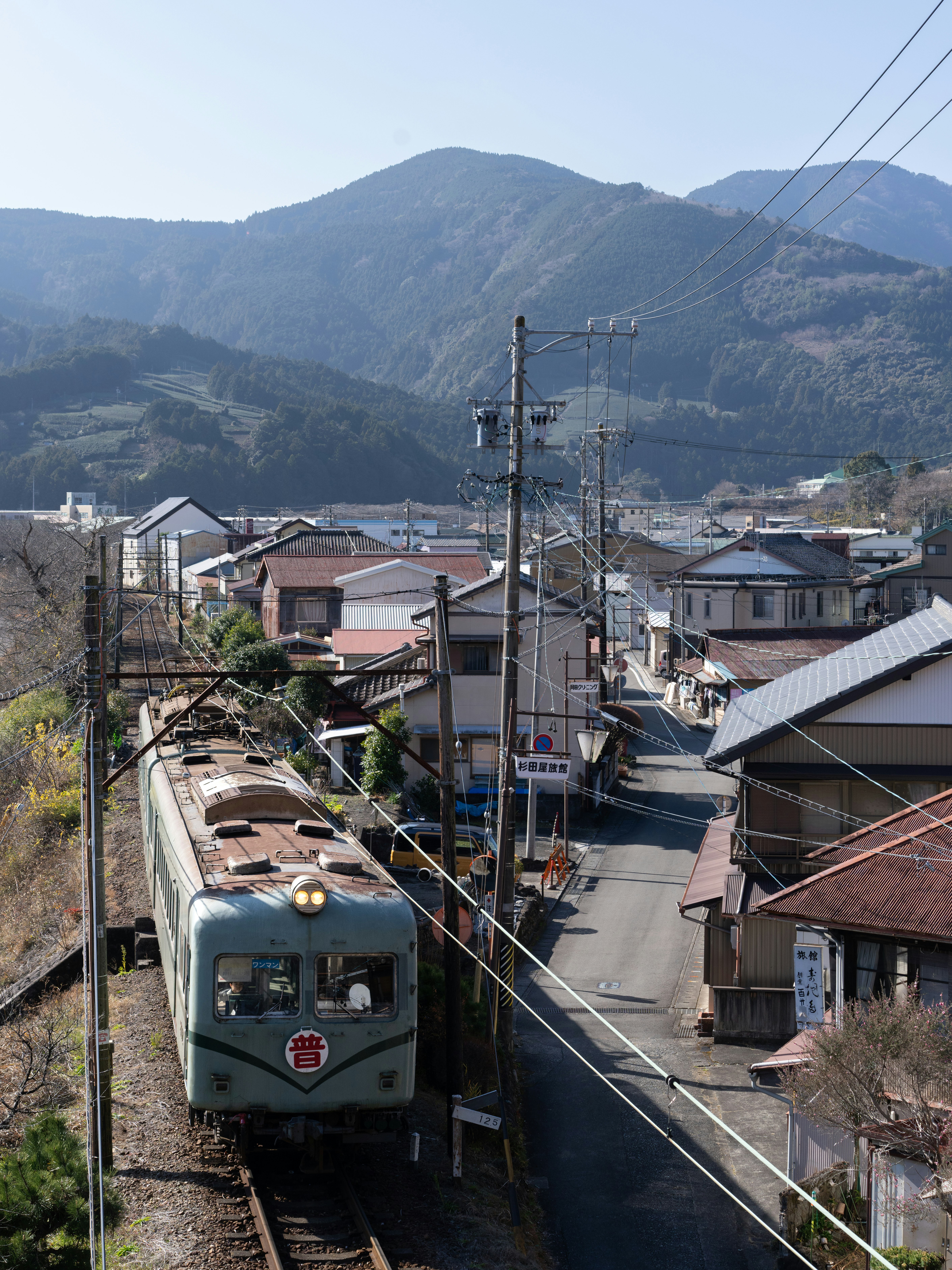山あいの住宅地を走るローカル列車の車窓風景