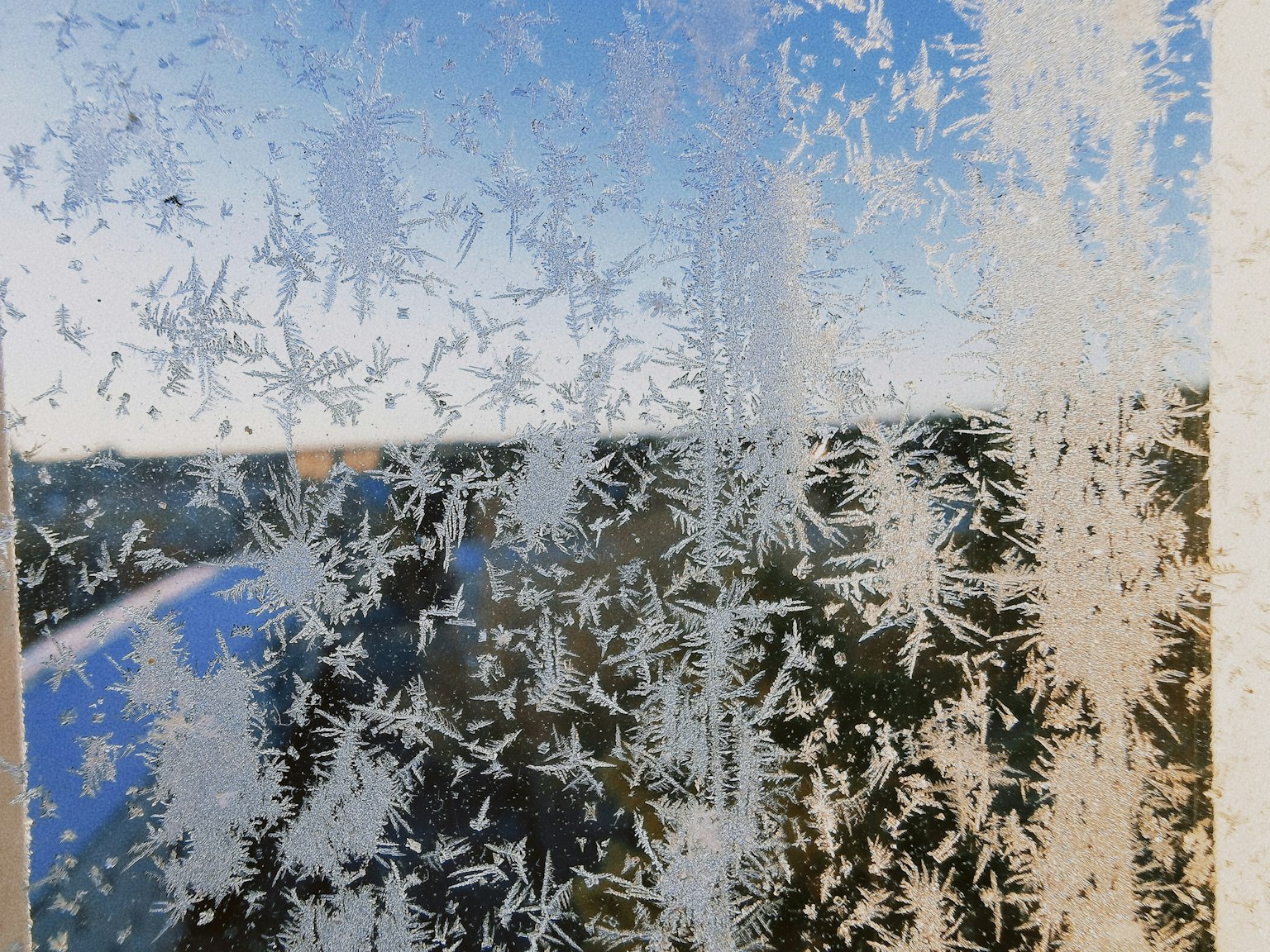 結冰的窗戶，細緻的冰晶透出藍天和景色