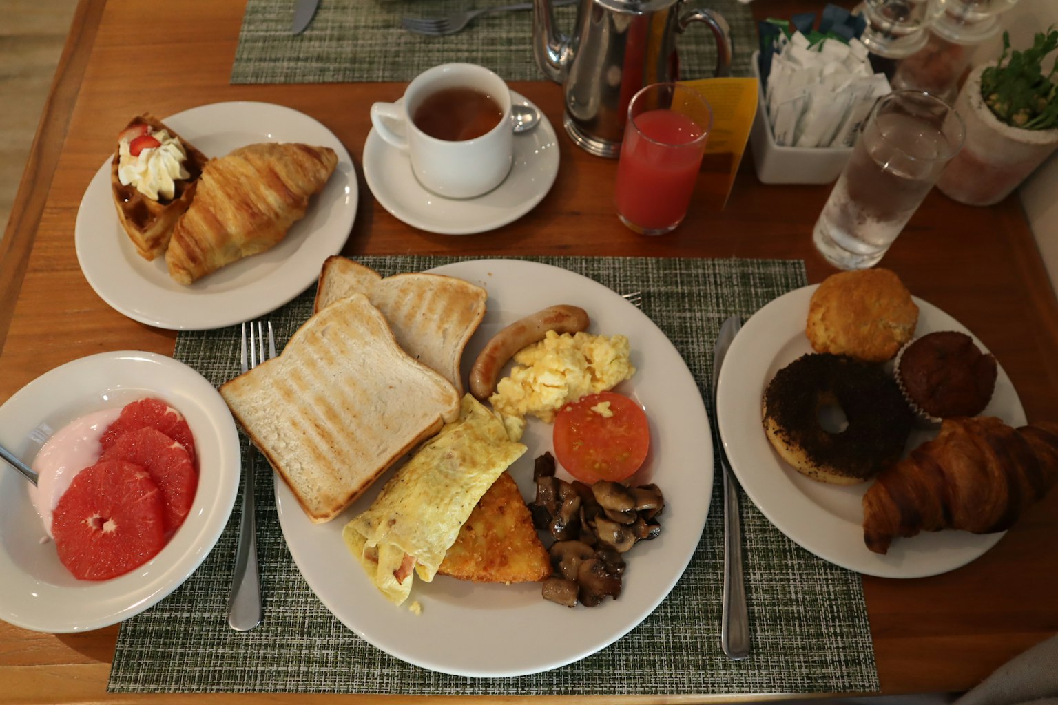 Table de petit-déjeuner avec des toasts des œufs brouillés des tomates des champignons des croissants et un dessert