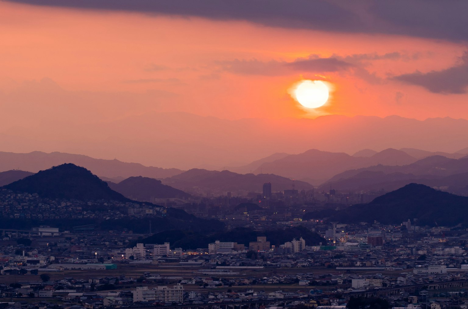 Vue panoramique d'un coucher de soleil entre les montagnes avec un ciel orange et violet