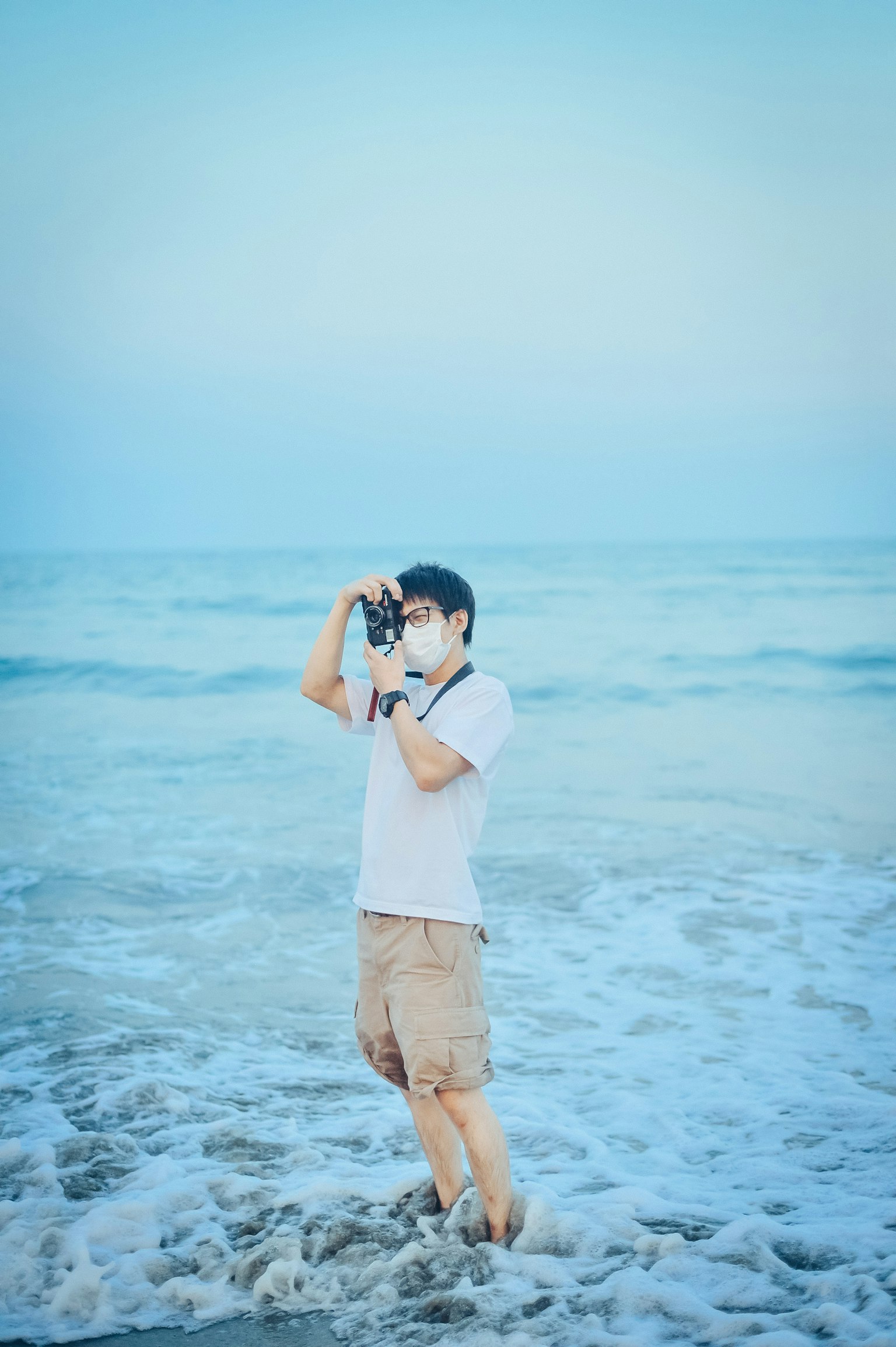 A man holding a camera at the beach