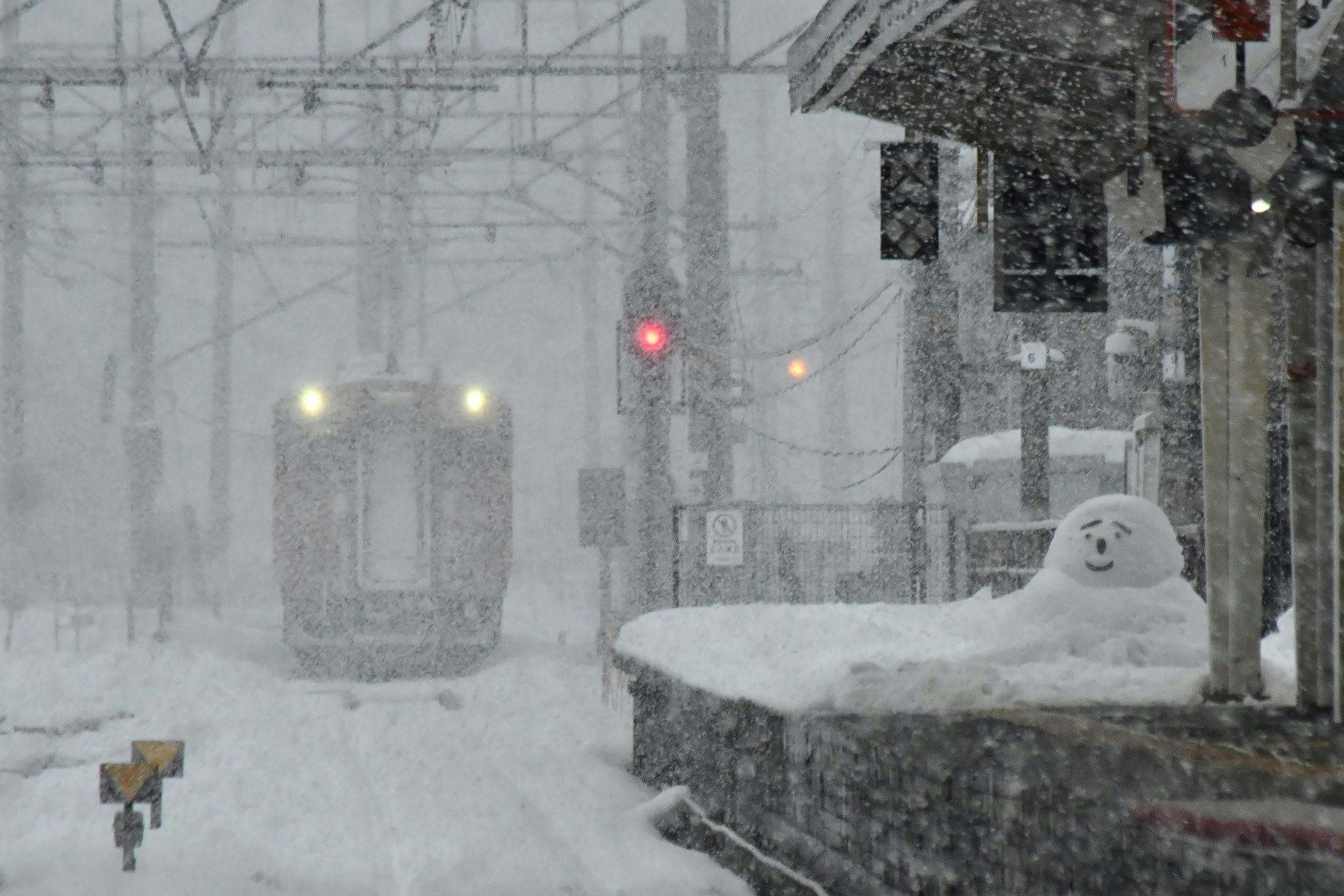 snow falling inside a train station with snow-covered bench