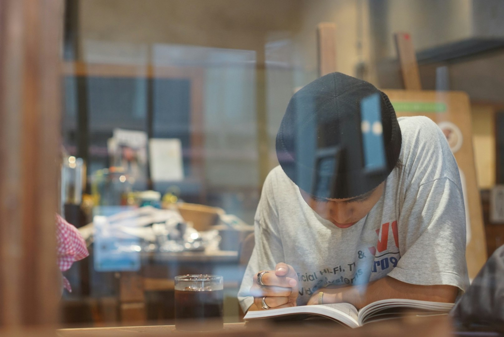 Scena di studio in interni con una persona che legge un libro vista attraverso una finestra