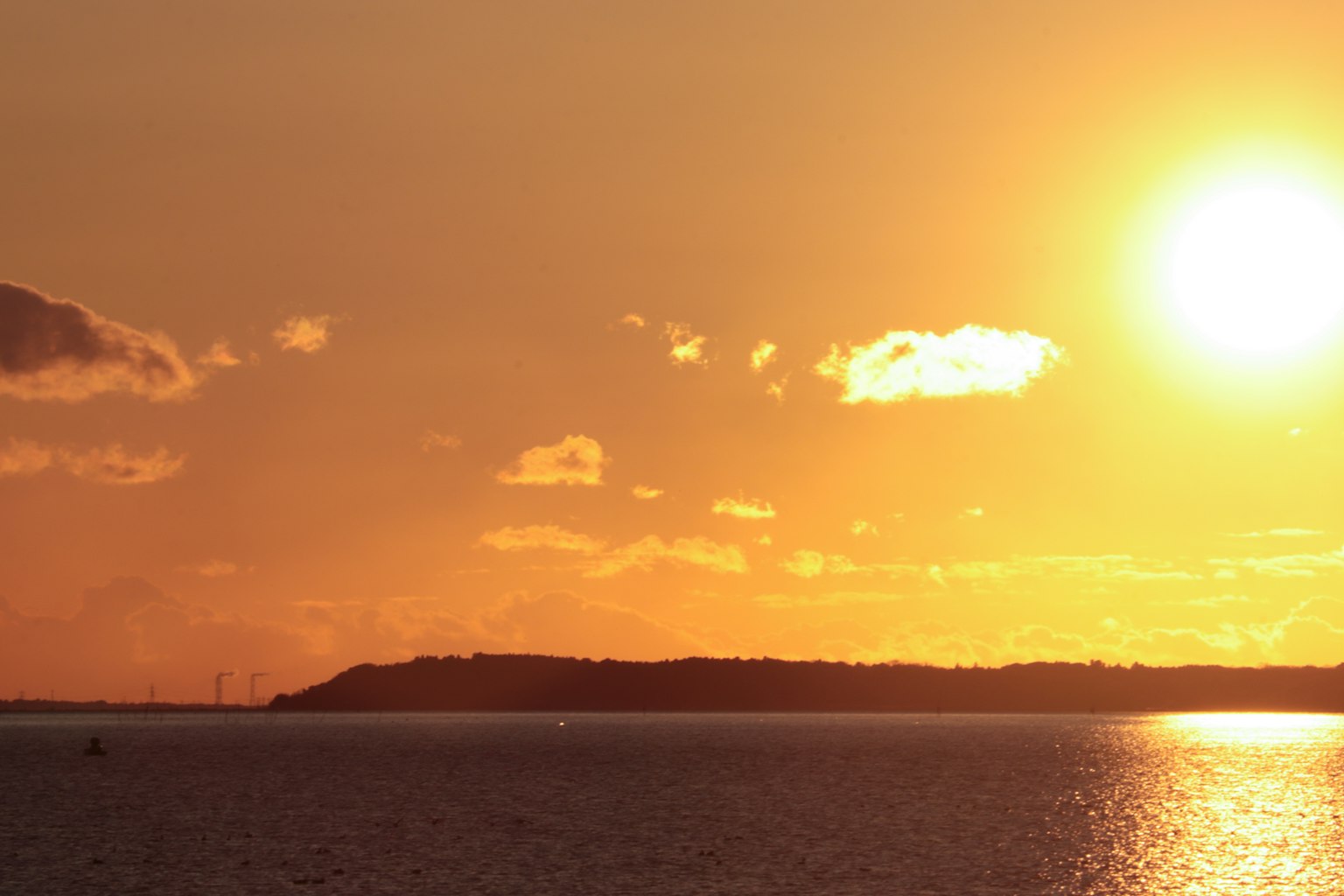 Tramonto suggestivo sull'oceano con nuvole e colline lontane