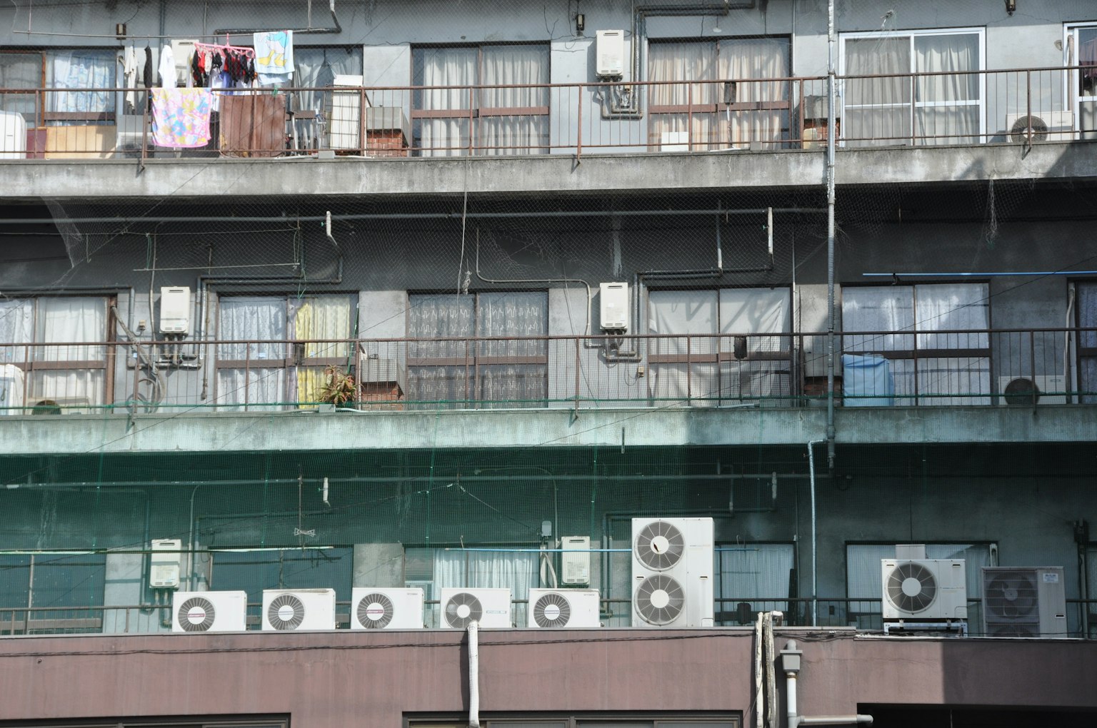 Extérieur d'un ancien immeuble d'appartements avec plusieurs climatiseurs et du linge suspendu