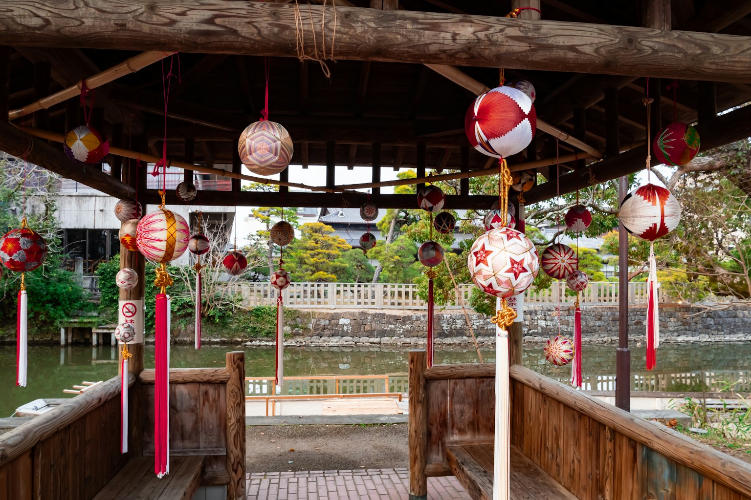 Lanternes colorées suspendues dans un pavillon en bois surplombant une vue sereine sur l'eau