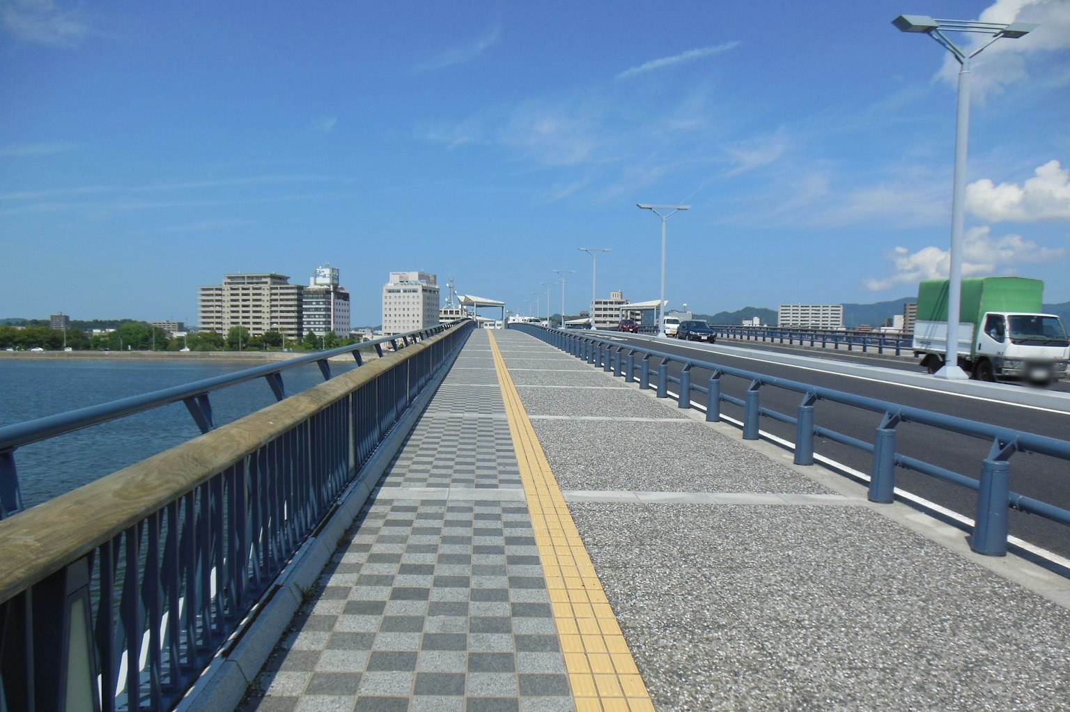 Wide pedestrian bridge with a checkered pattern under a blue sky
