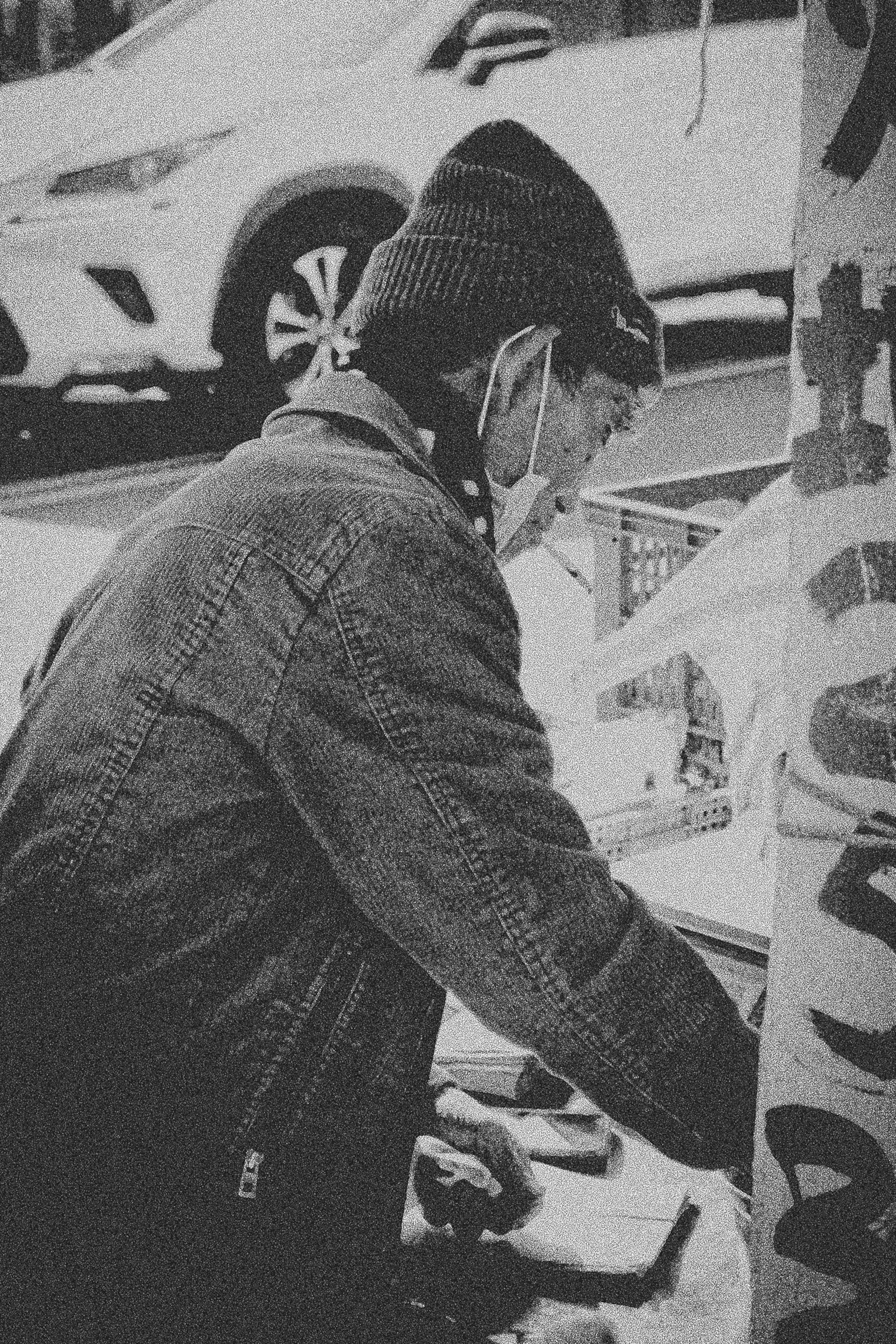A man working in a monochrome image with a car in the background