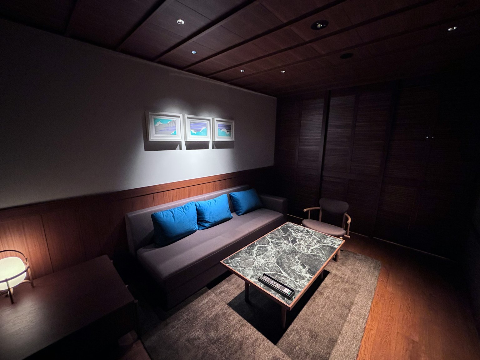 Gemütlicher Raum mit dunklem Holzinterieur blauen Kissen auf einem Sofa und einem Marmortisch