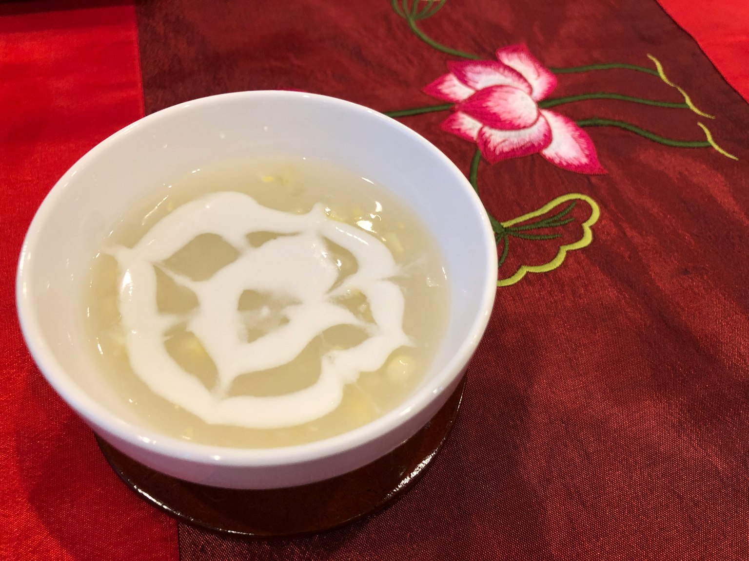 透明甜点碗上有白色奶油设计，红色桌布上有粉色花卉刺绣