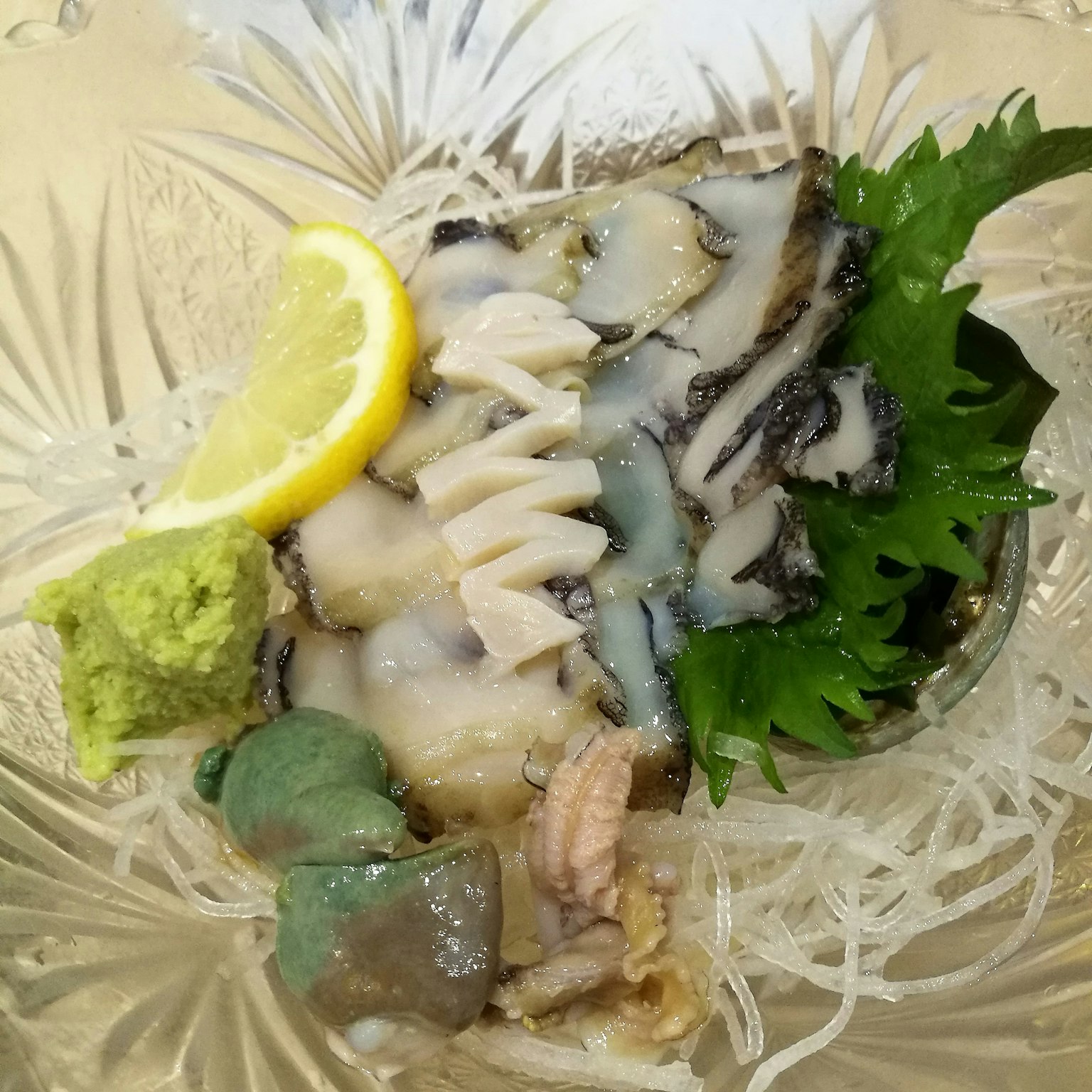 Plato de sashimi fresco con guarniciones de limón y wasabi
