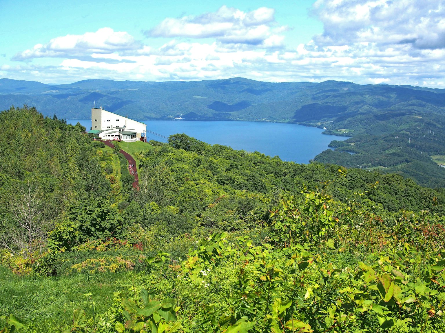 A white building surrounded by a beautiful lake and mountains