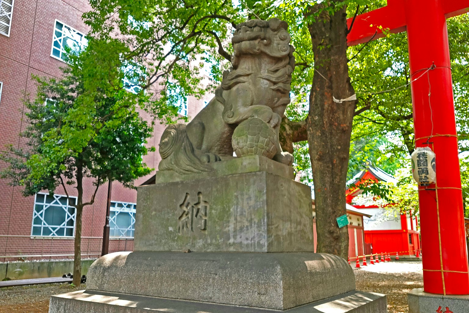 Stone komainu statue stands in a lush green setting at a shrine