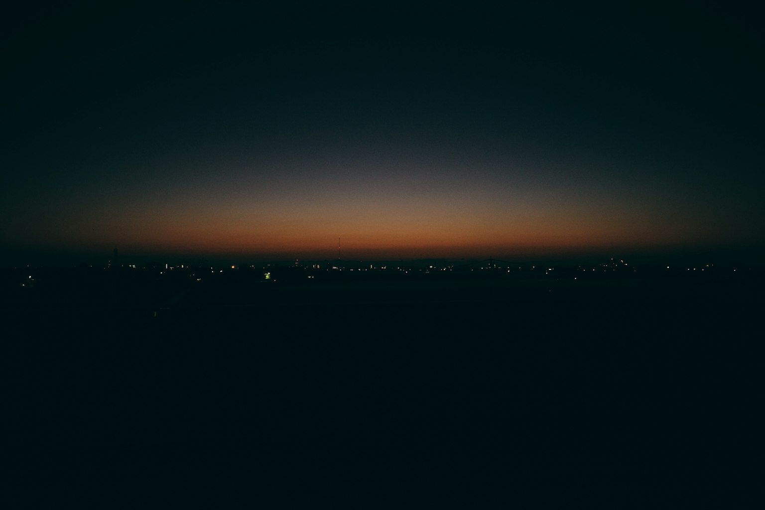 Twilight sky with a dark horizon and distant city lights