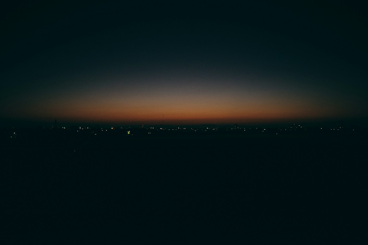 黄昏天空，黑暗地平线和远处的城市灯光