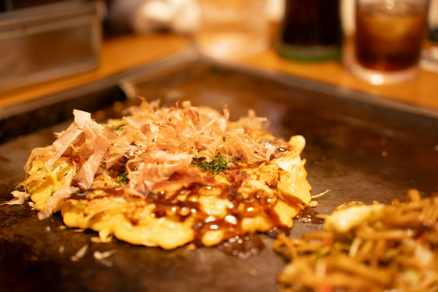 Okonomiyaki cubierto con copos de bonito y salsa