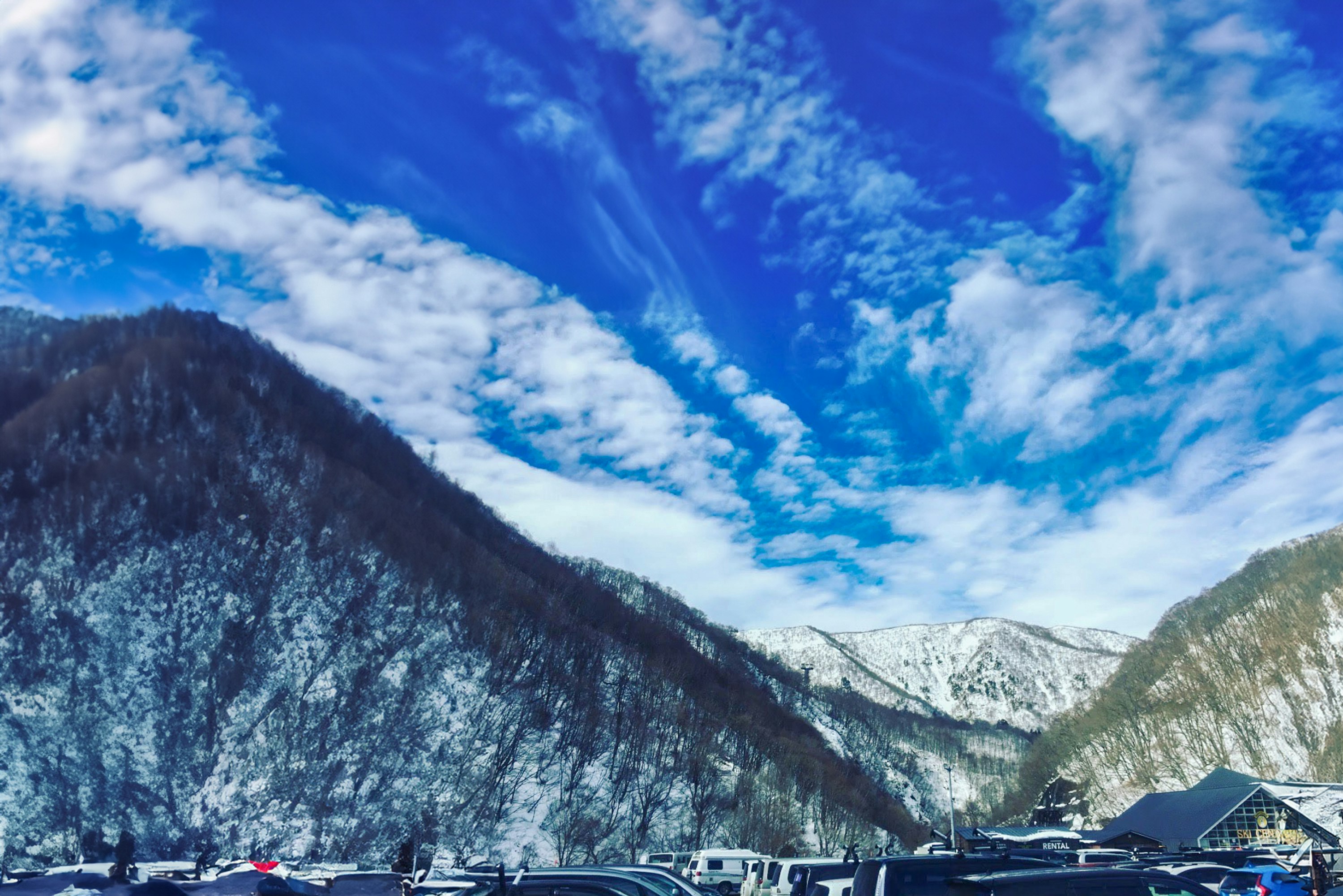Parkplatz mit schneebedeckten Bergen und blauem Himmel
