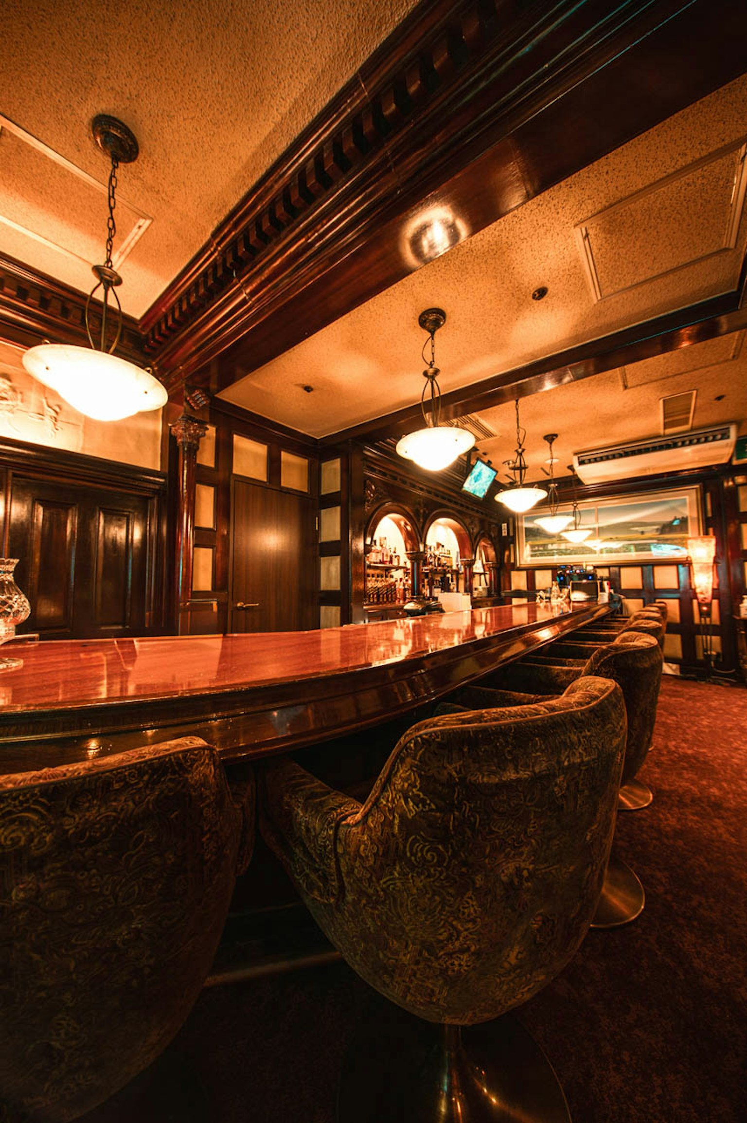 Diseño interior de bar elegante con madera oscura y asientos de terciopelo