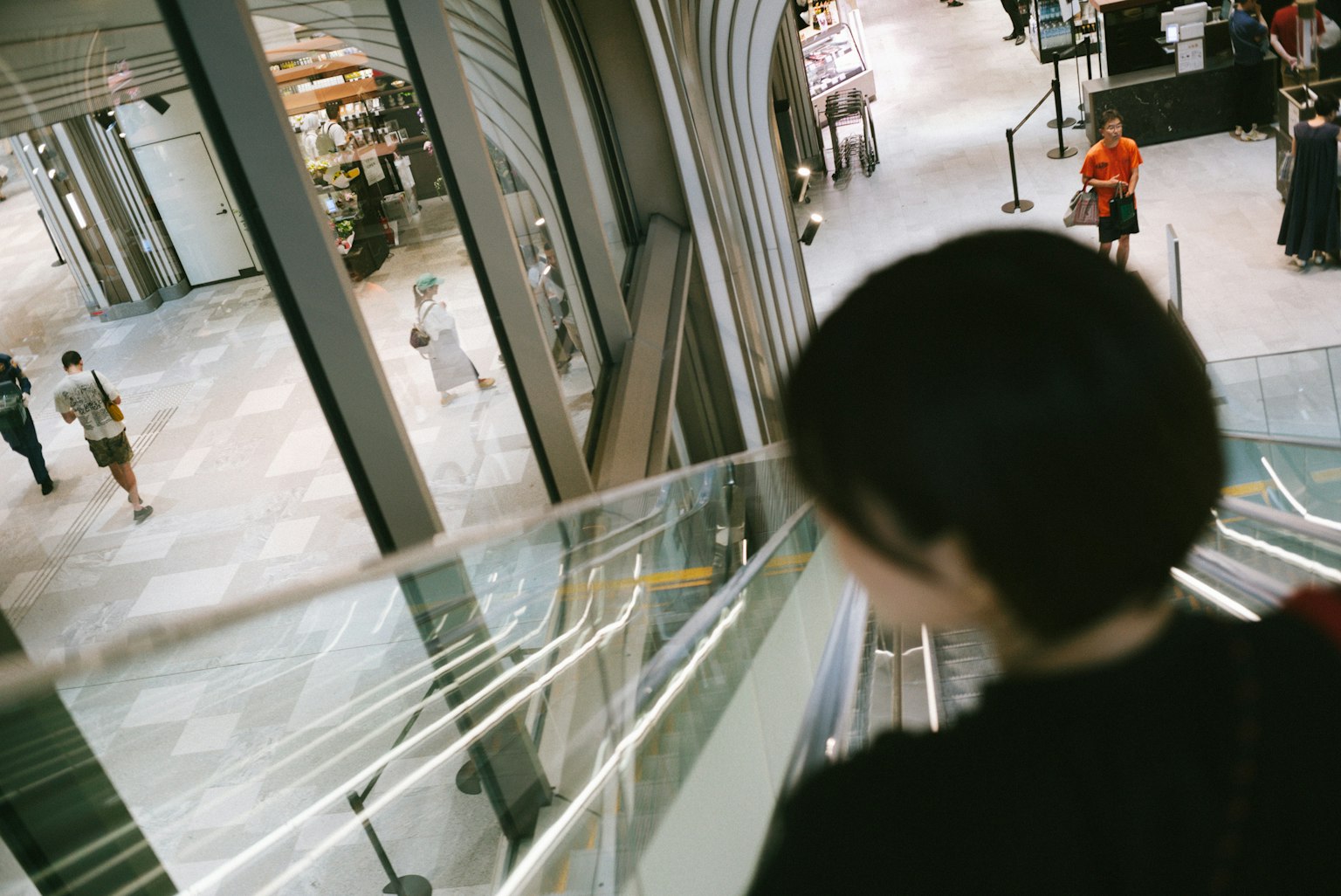 Une femme descendant un escalator dans une zone commerciale moderne