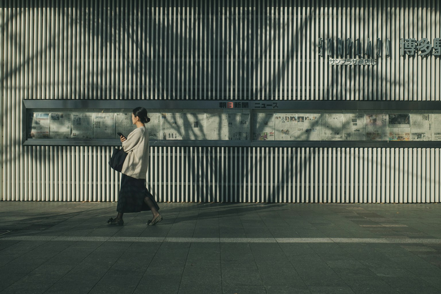 그림자가 드리워진 벽 앞을 걷는 여성의 실루엣