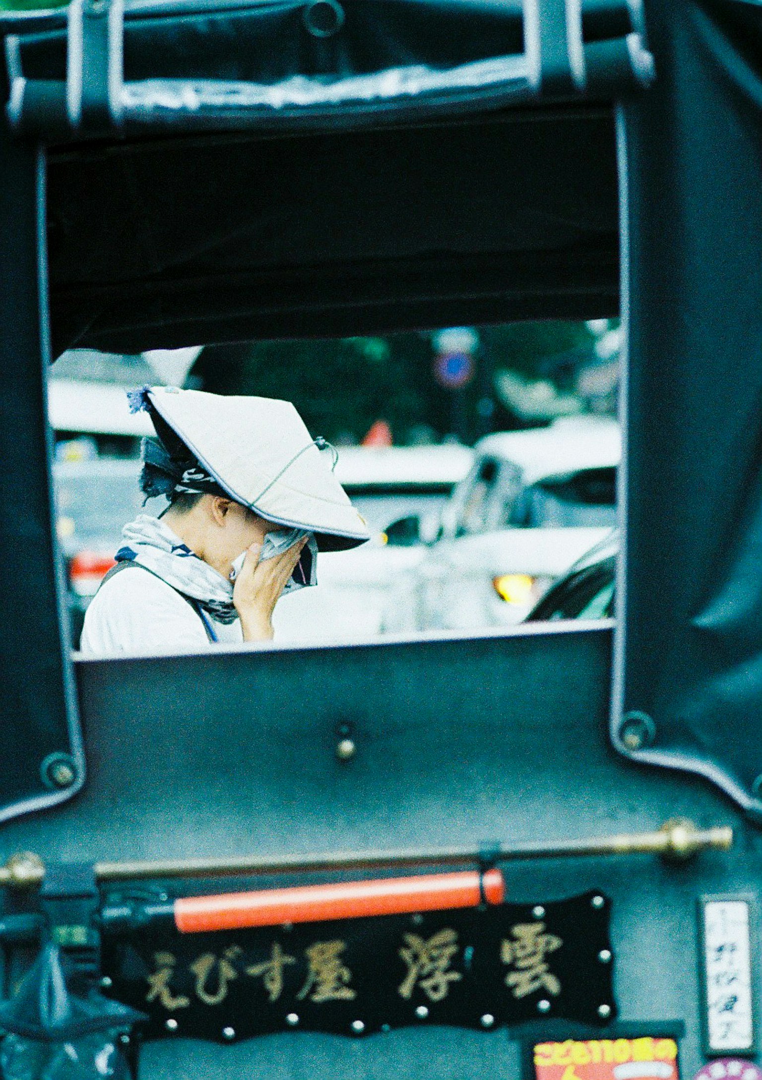 Rickshaw driver wearing a hat looking out at the street