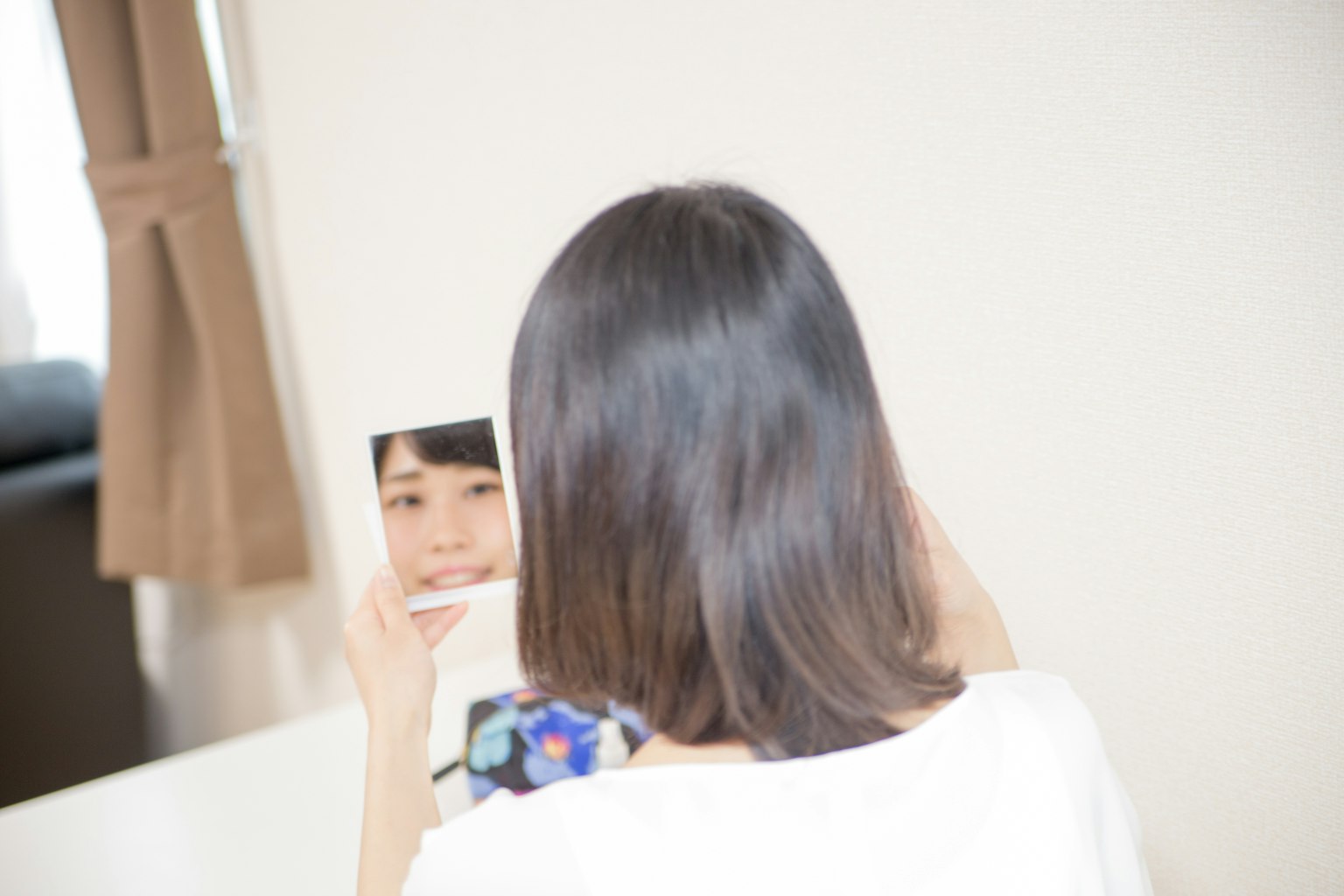 Une femme regardant son reflet dans un miroir de dos Cheveux de longueur épaule Lumière naturelle douce illuminant la pièce