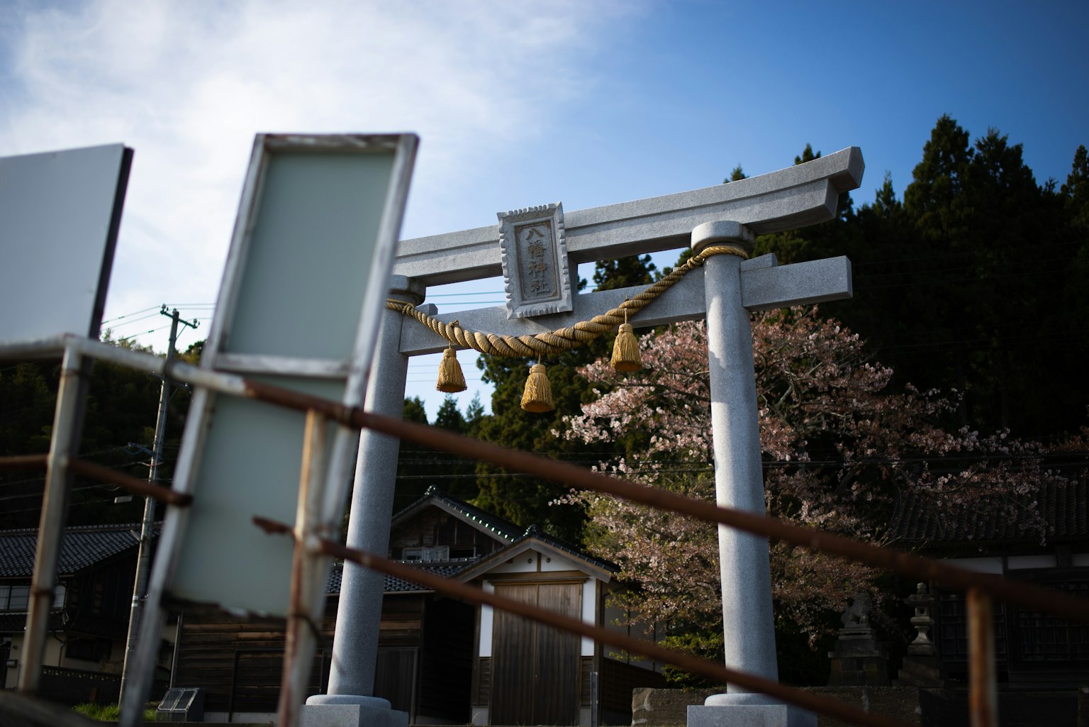 Un portail torii blanc avec un arbre de cerisier dans un paysage de sanctuaire