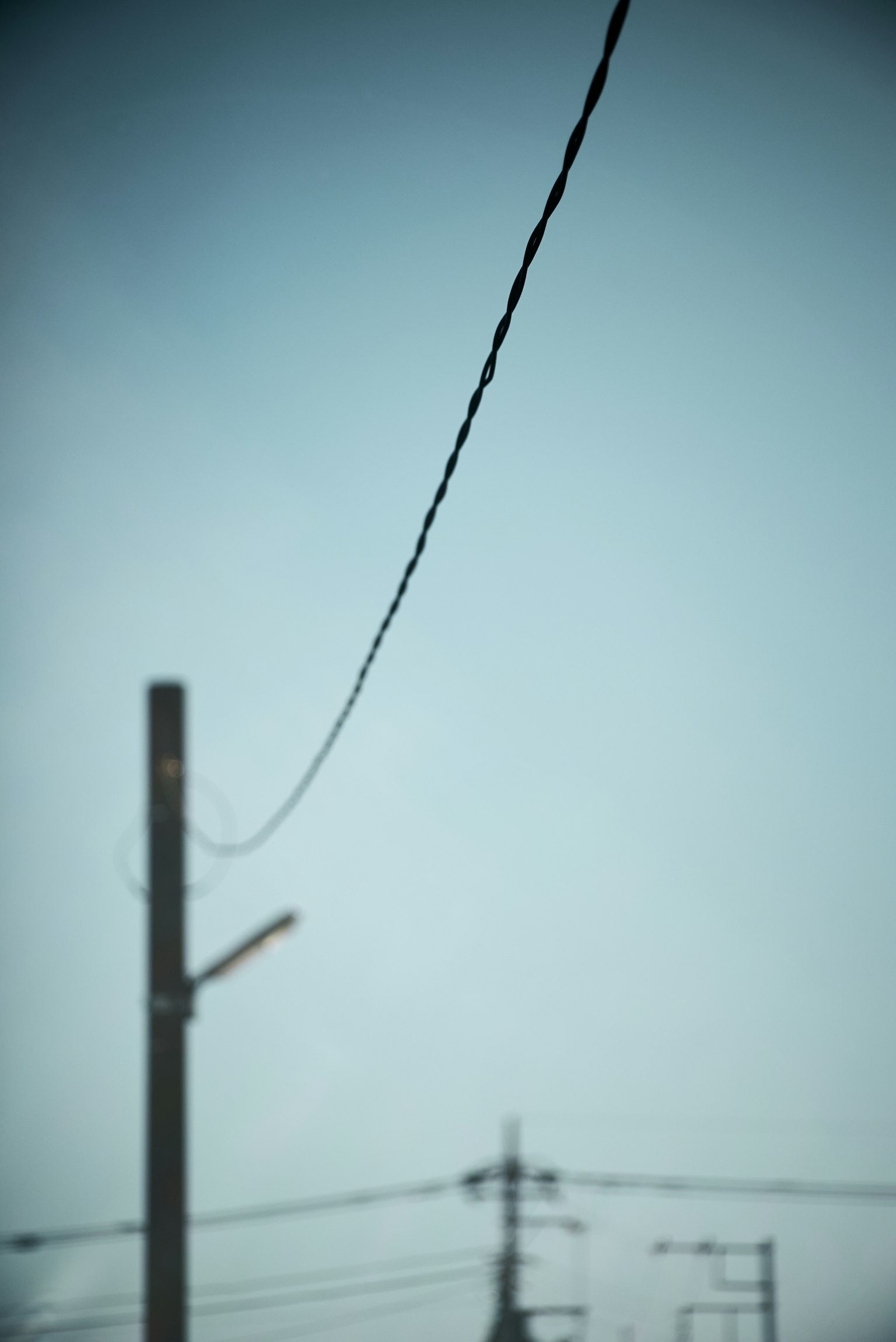 Primer plano de un poste de electricidad y un cable contra un cielo azul