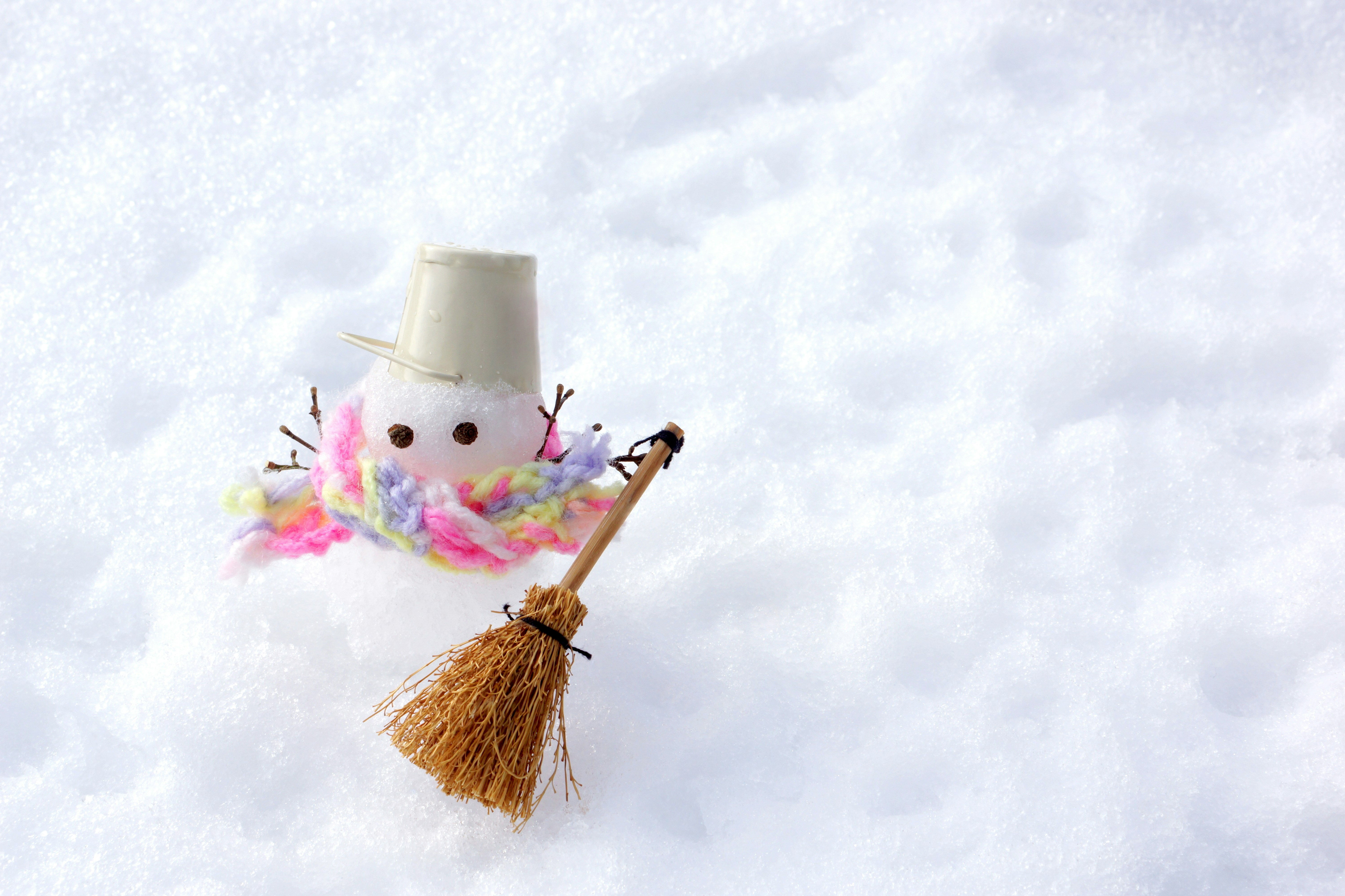 small snowman decoration on snow with a broom