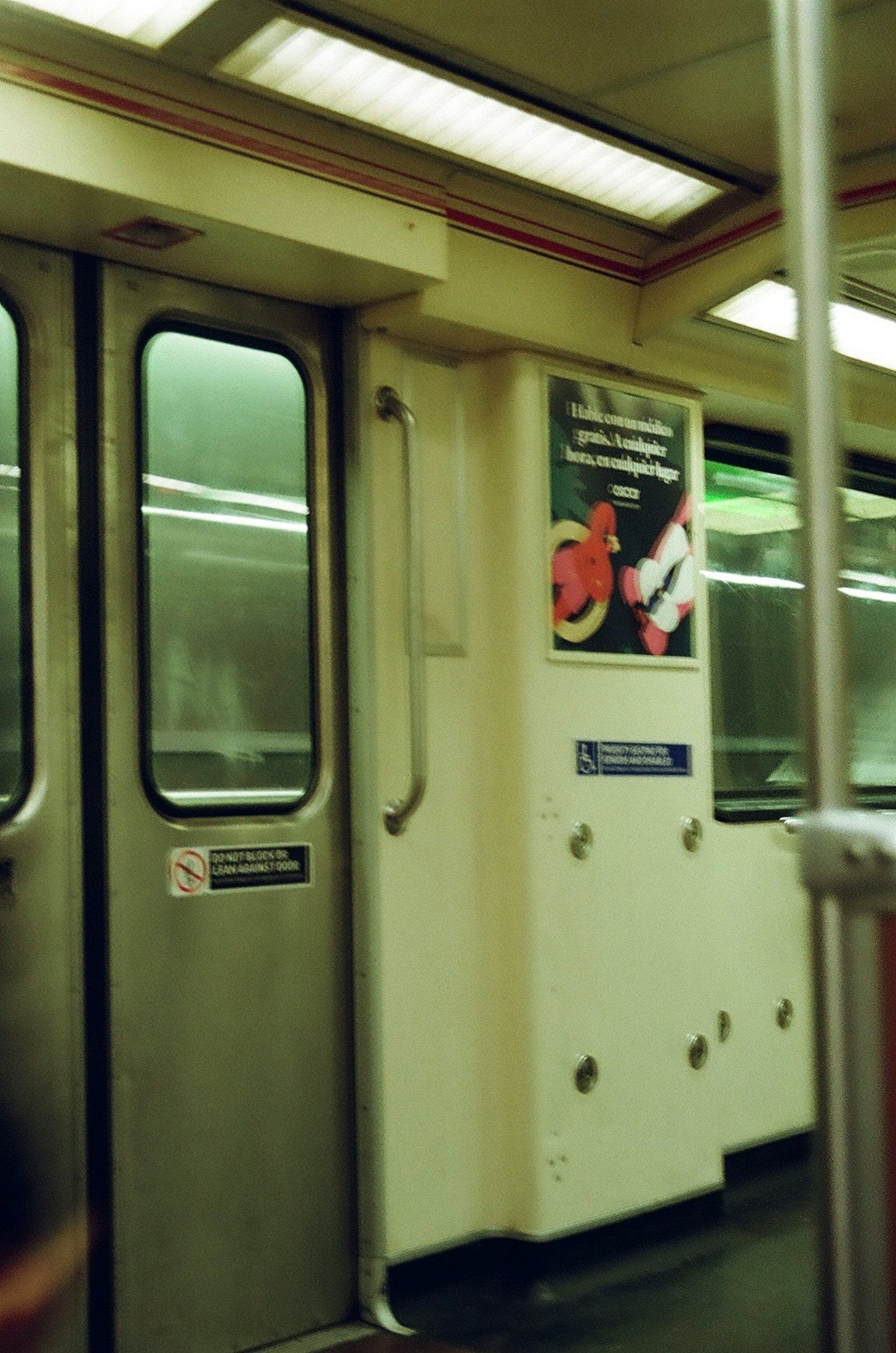 Interior of a subway car featuring doors and an advertisement on the wall