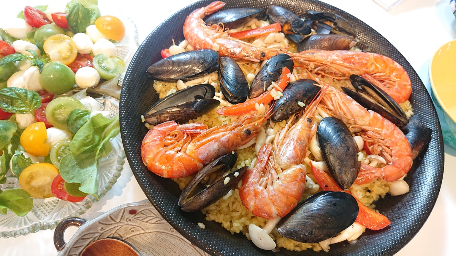 Meeresfrüchte-Paella in einem schwarzen Gericht mit Beilagensalat serviert