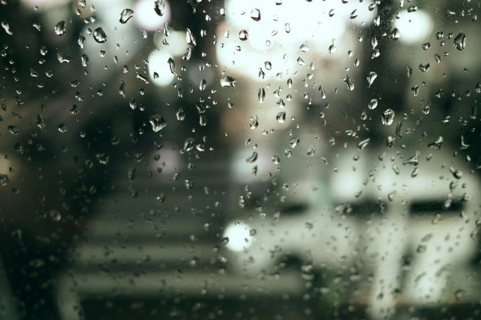 Scène urbaine floue vue à travers une fenêtre couverte de gouttes de pluie