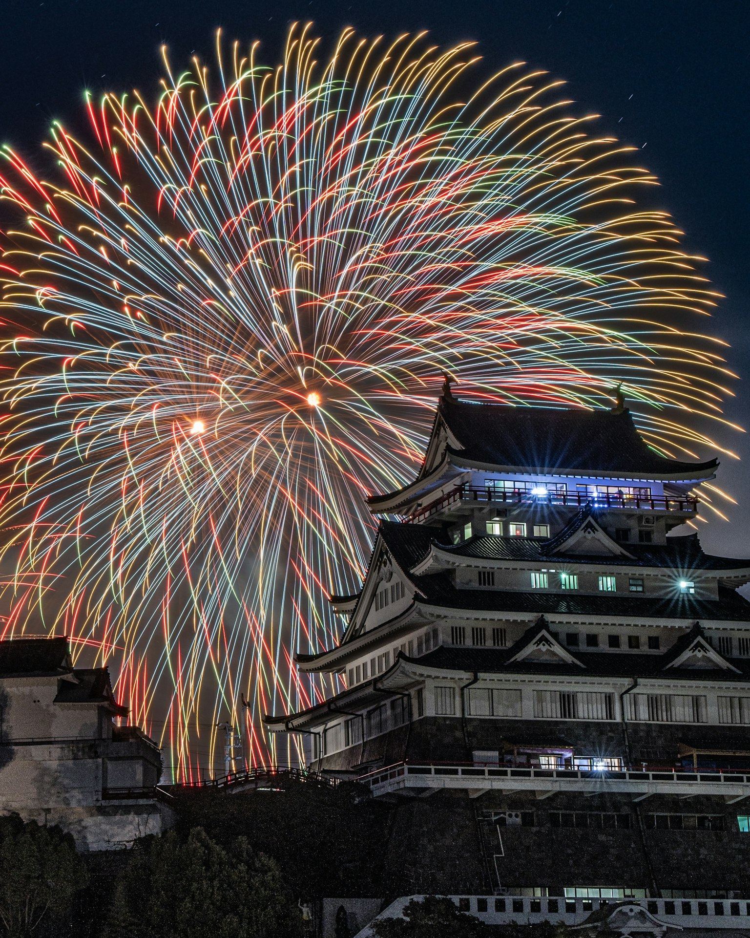 การแสดงดอกไม้ไฟที่สวยงามบนท้องฟ้ายามค่ำคืนพร้อมกับปราสาทญี่ปุ่น