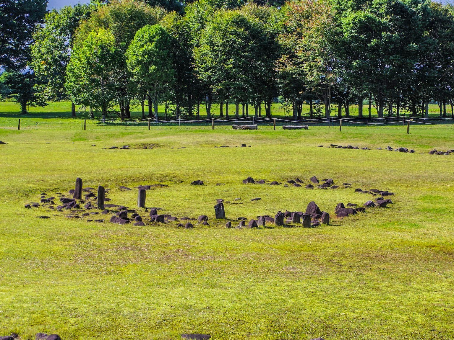 Landscape of a stone circle ruin surrounded by lush green grass