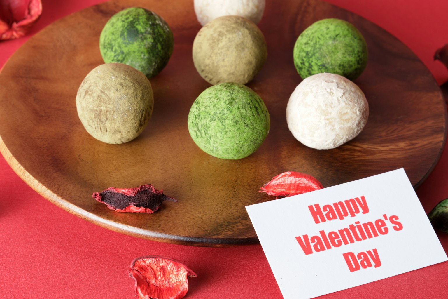 Boules colorées disposées sur une assiette en bois avec une carte disant Joyeuse Saint-Valentin
