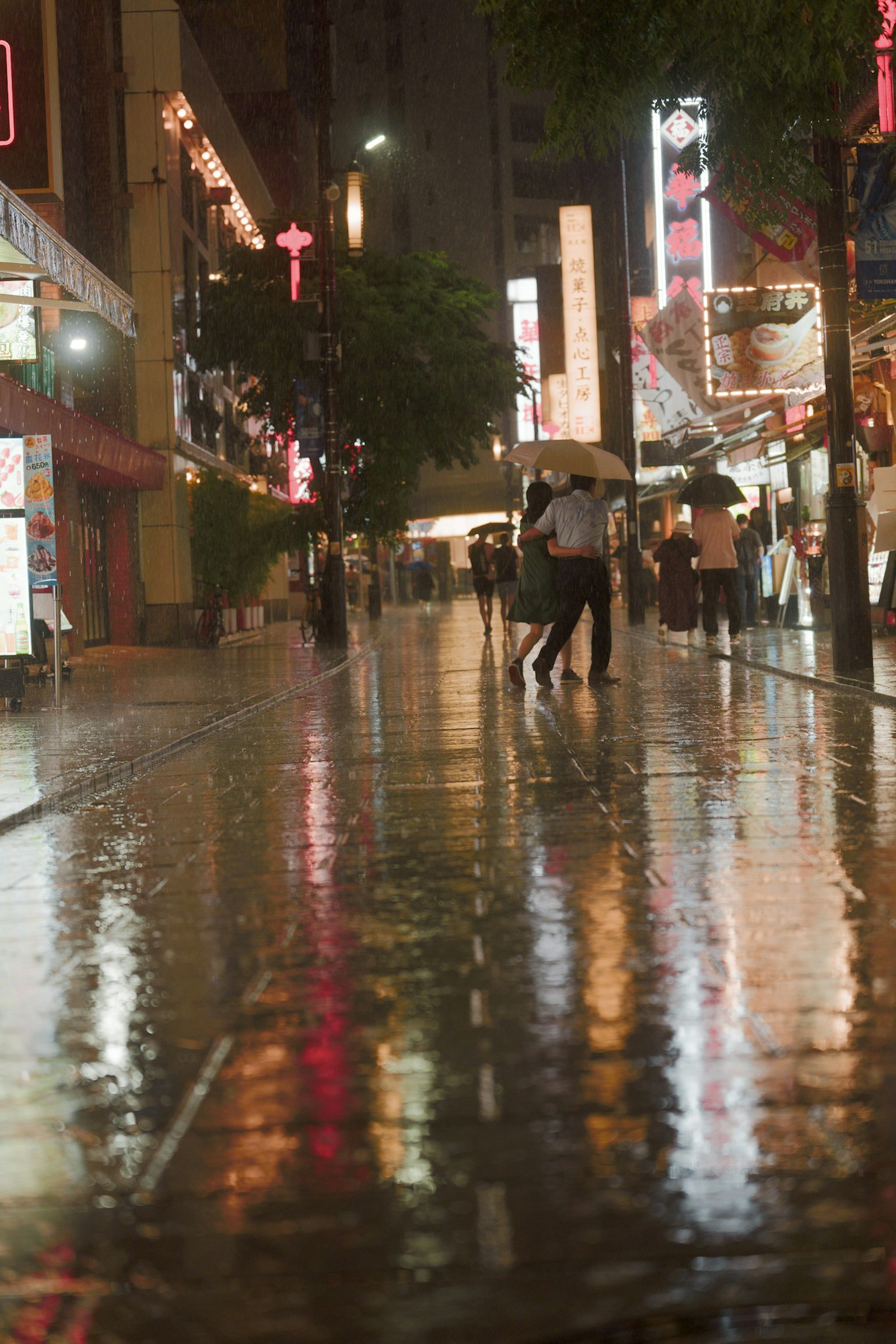 雨水浸湿的街道夜景 人们撑着伞走在反射的霓虹灯下