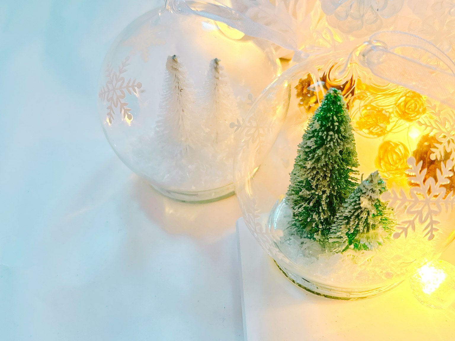 Decorazioni in vetro trasparente con un piccolo albero verde e decorazioni simili alla neve