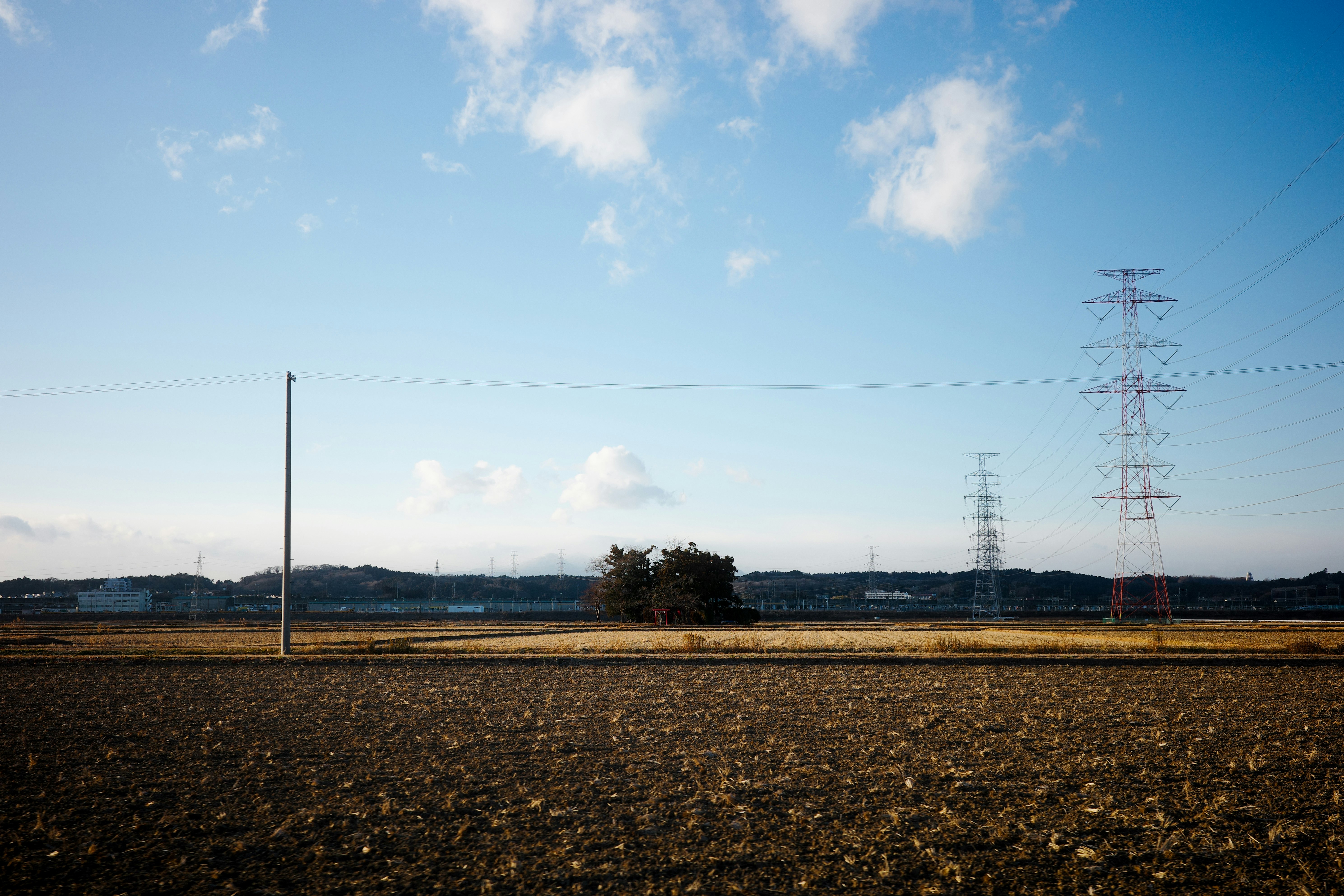 A landscape of blue sky over fields with power transmission towers