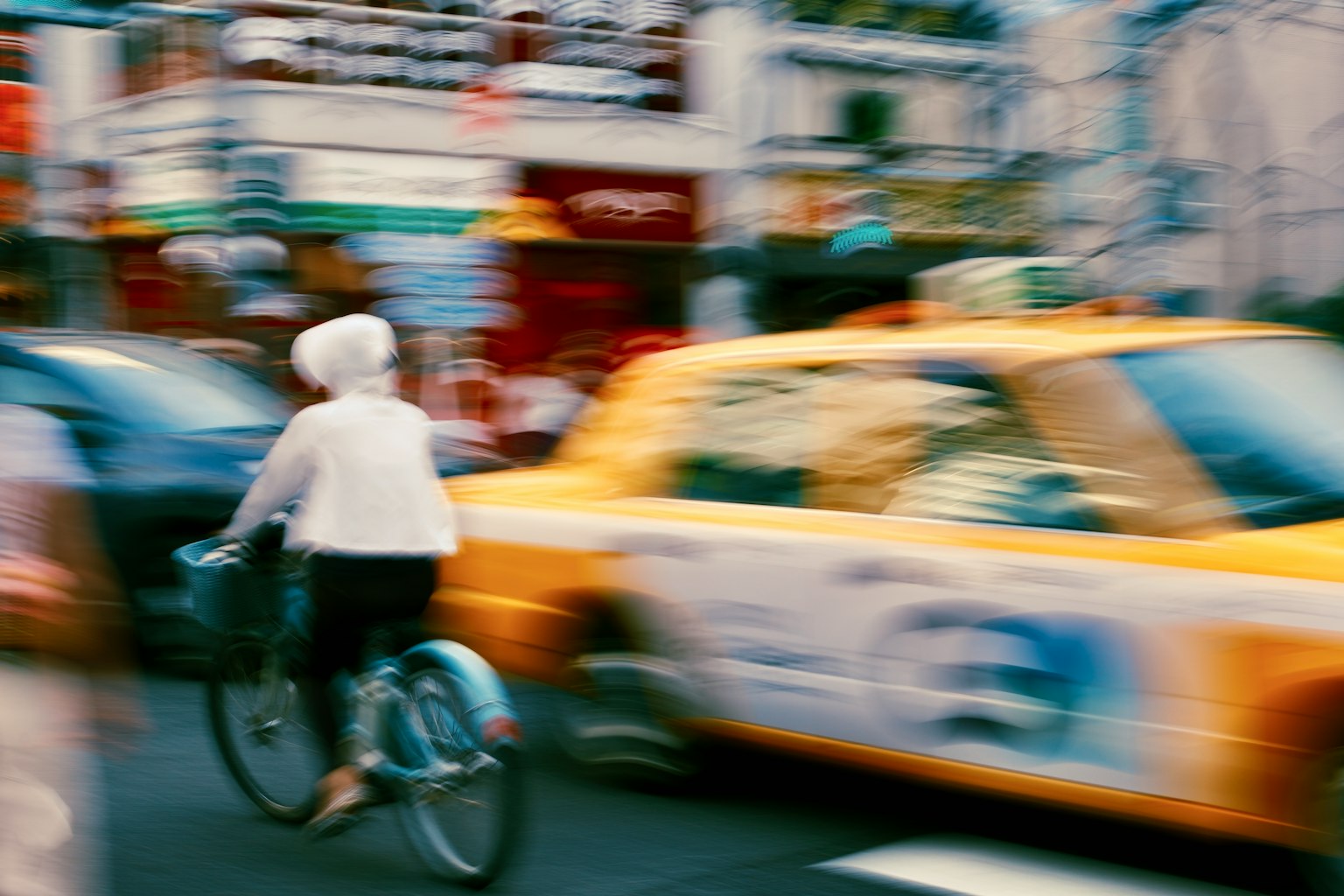 自転車に乗る高齢者と動くタクシーのぼやけた都市の風景