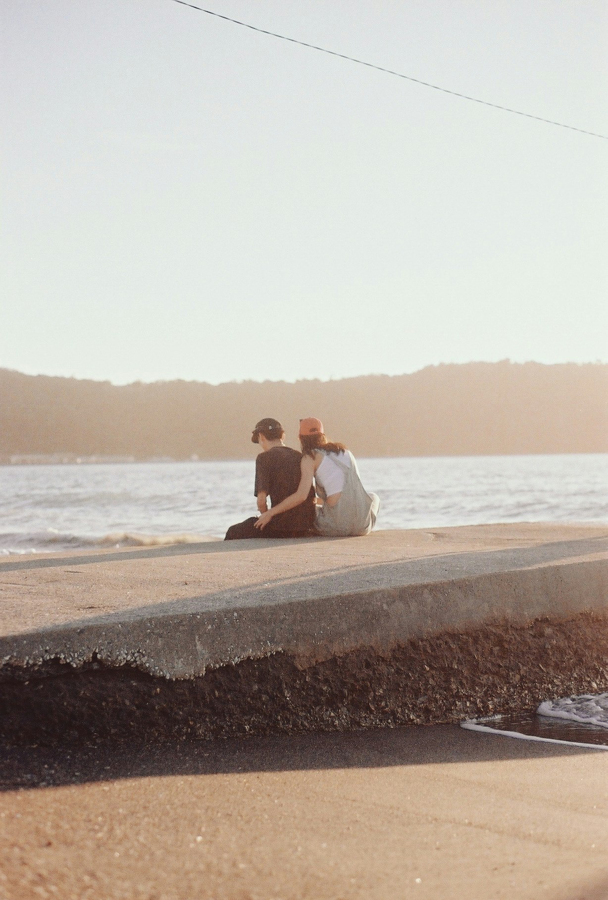 a couple sitting on a sandy beach at sunset