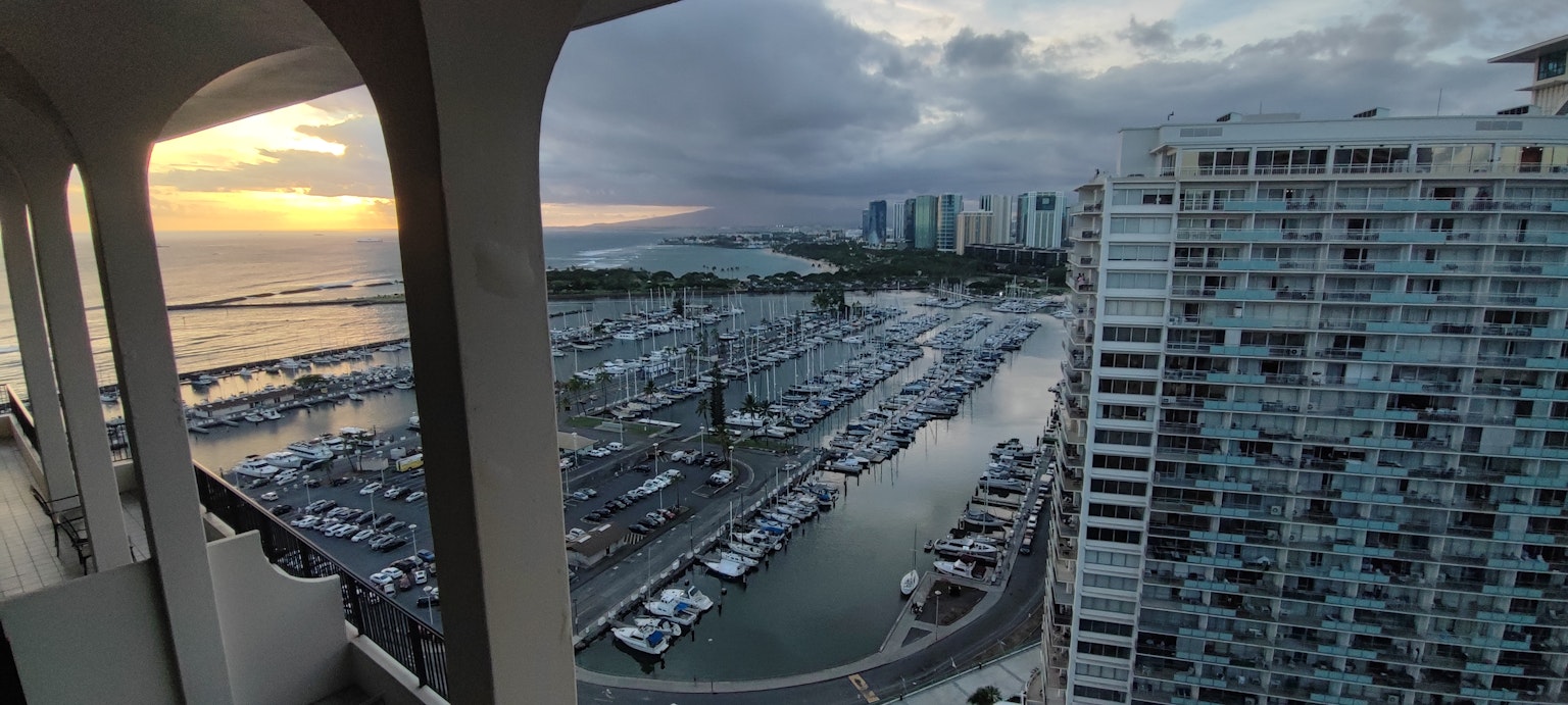 Panoramic view from a high-rise building showing a marina and sunset sky