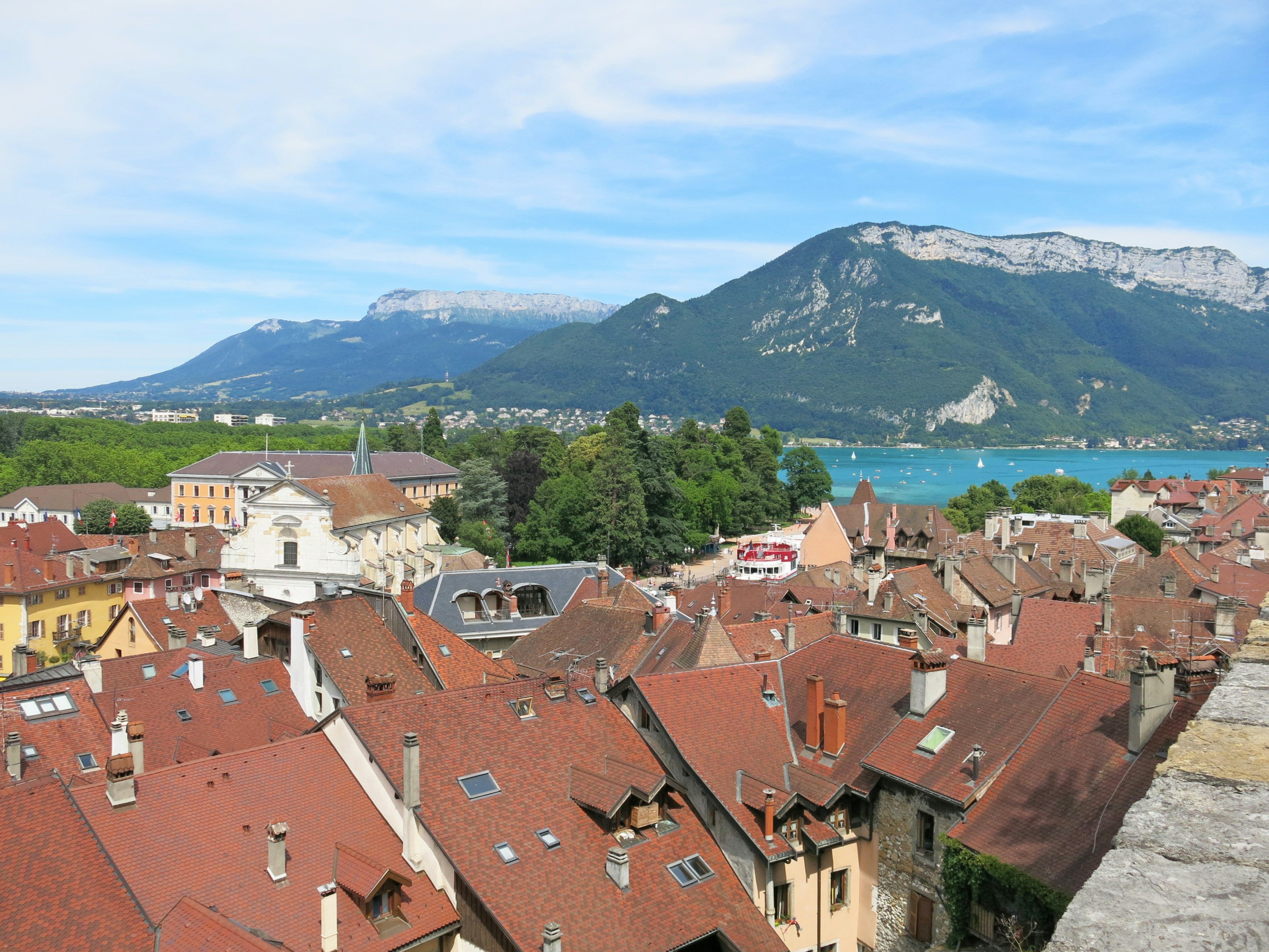 View of a town with red rooftops, mountains and a lake