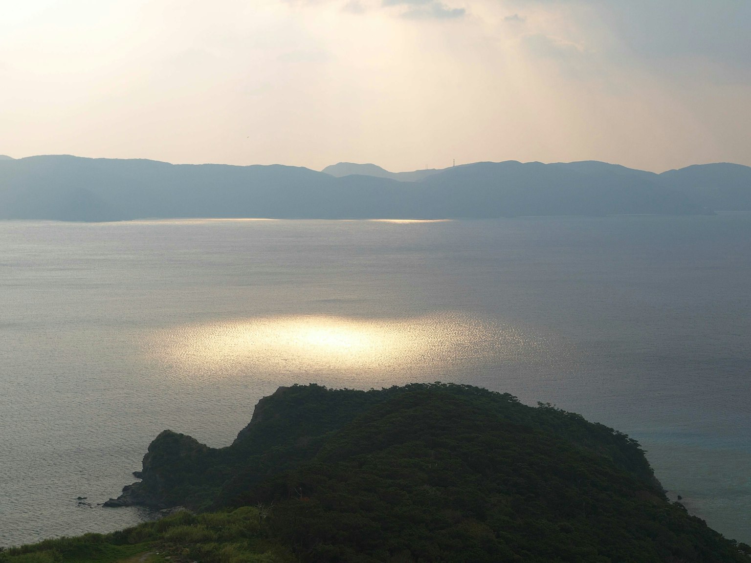Vue sereine de la mer et des montagnes avec la lumière se reflétant sur la surface de l'eau