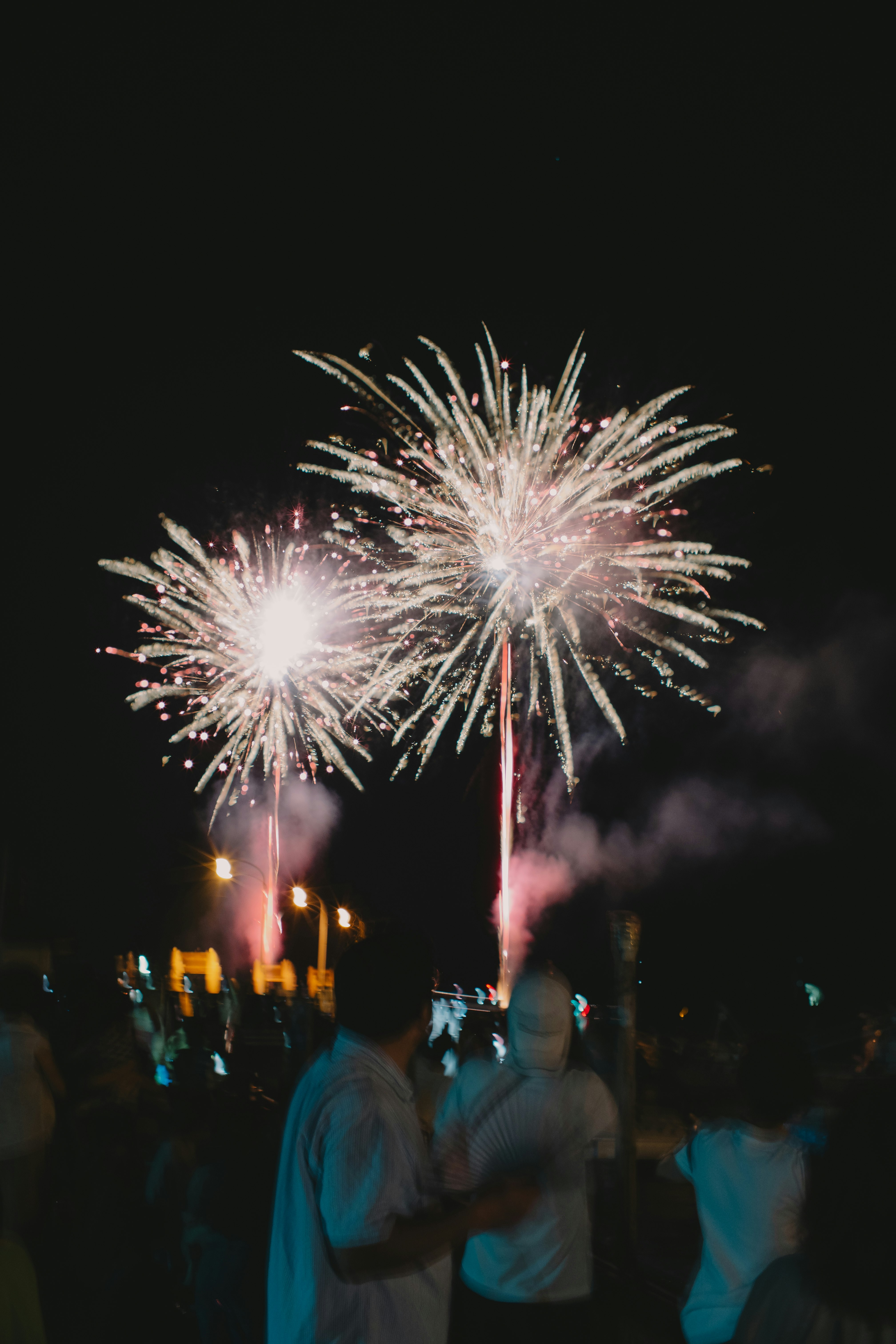 夜空に咲く花火と人々のシルエットの祭りの光景